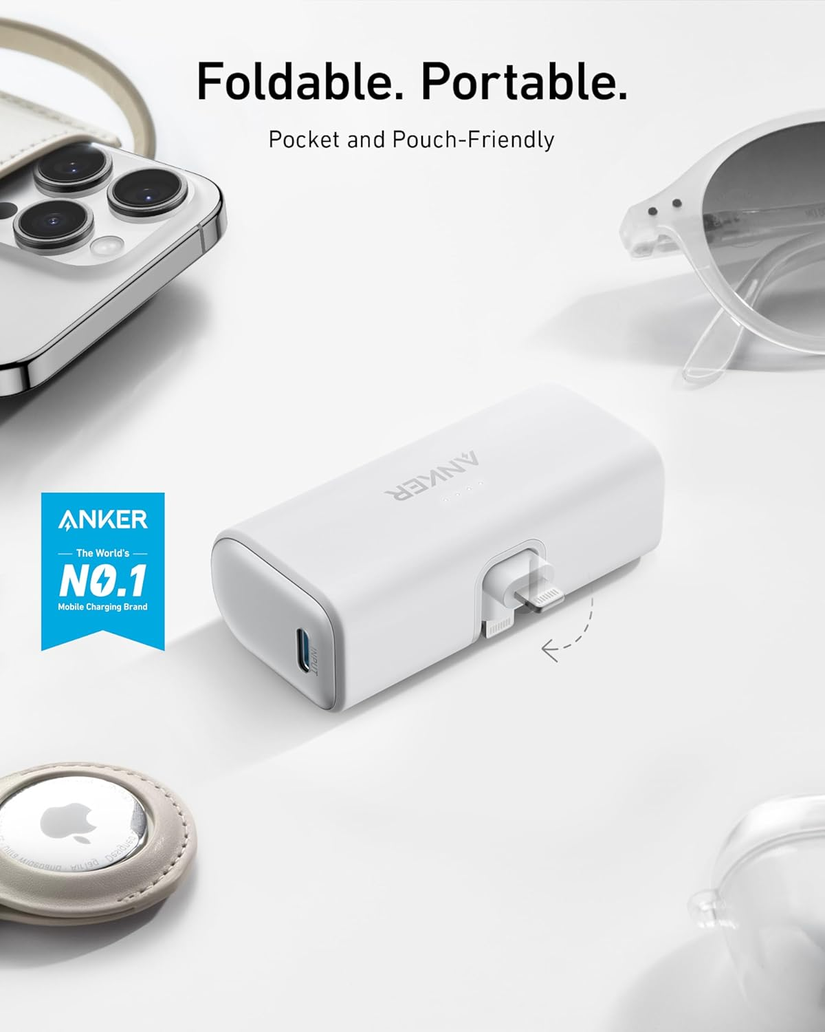 Beyaz bir ANKER güç bankası, iPhone, AirPods ve gözlük beyaz bir yüzeyde. Metin şöyle diyor: Katlanabilir. Taşınabilir.