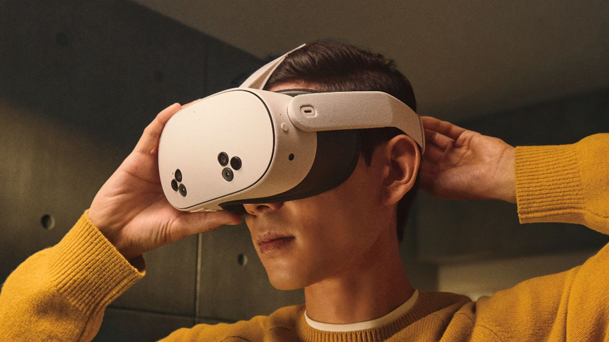 Adam VR başlığını ayarlıyor. Sarı kazak, karanlık arka plan.