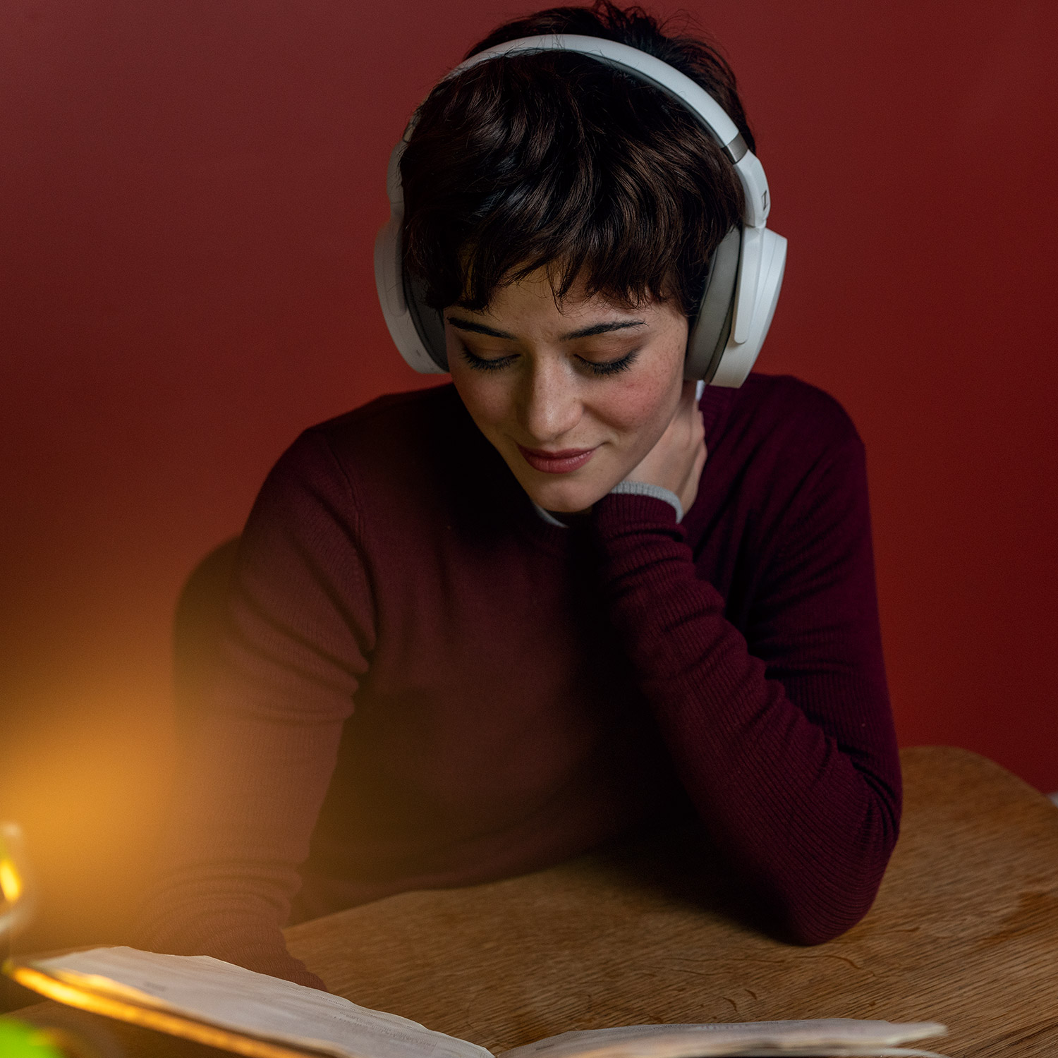 Egy nő fejhallgatóval olvas egy könyvet.