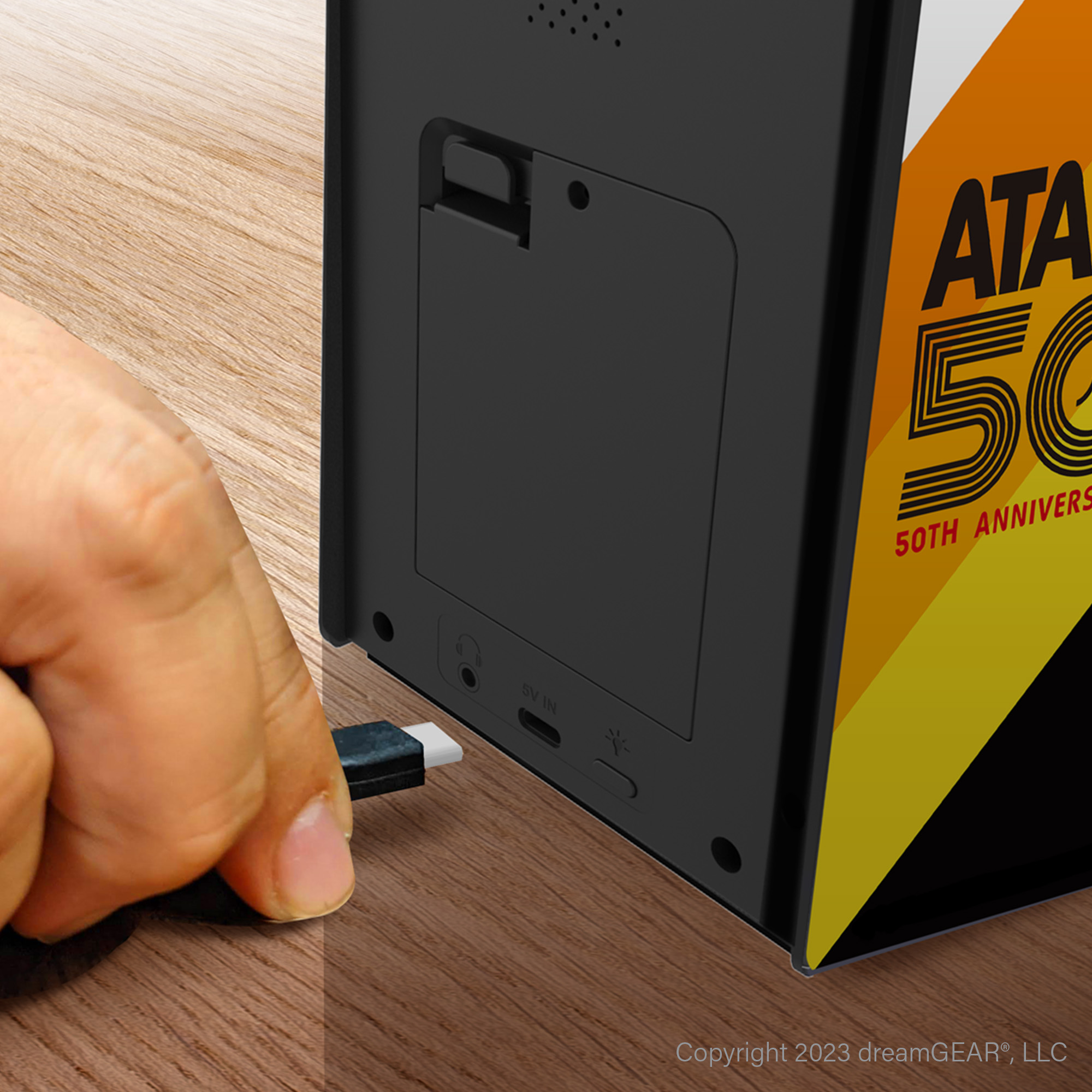 El, mini atari makinesinin arkasına bir USB-C kablosu bağlıyor.
