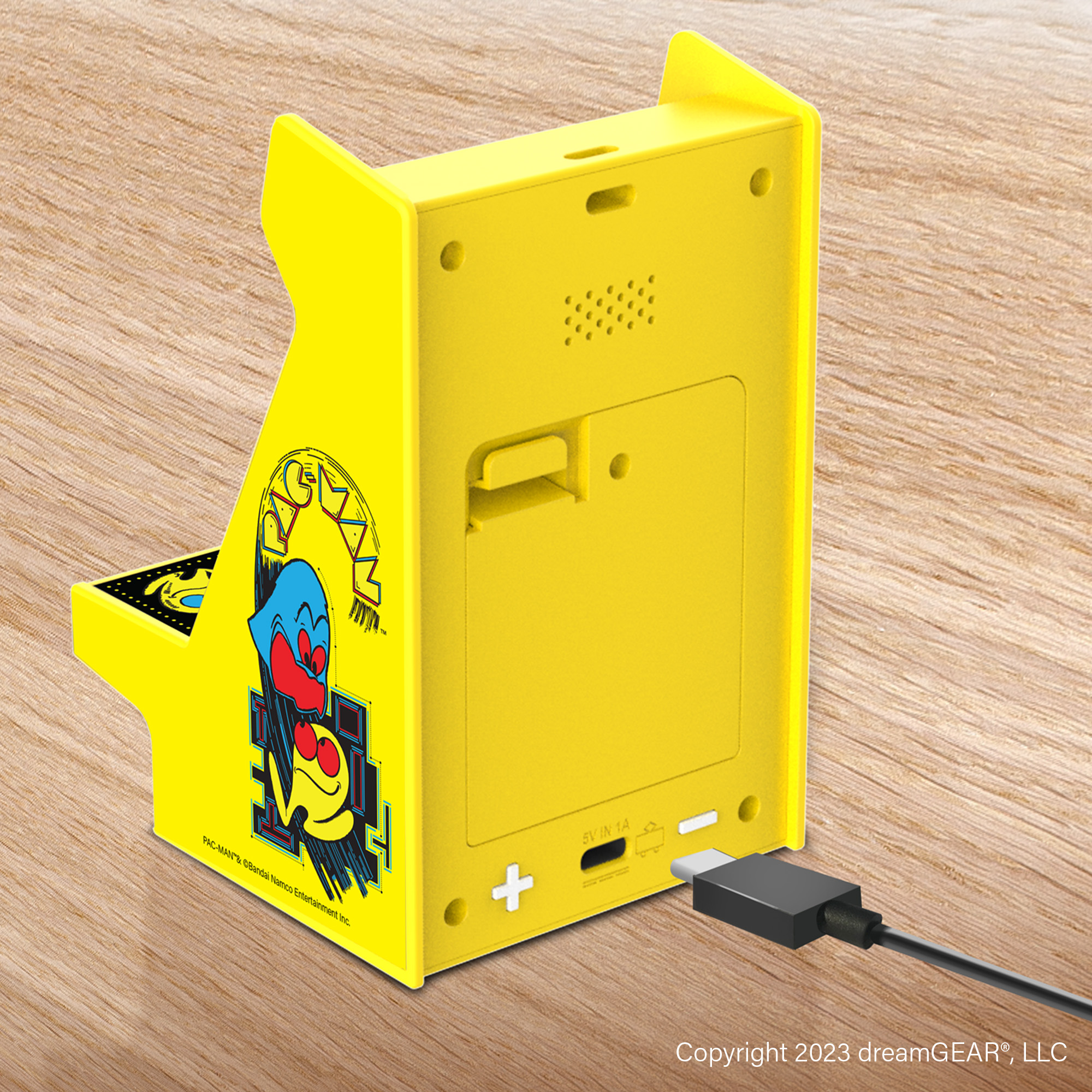 Sarı Pac-Man mini atari oyunu ve şarj kablosu. Ahşap yüzey arka planı.