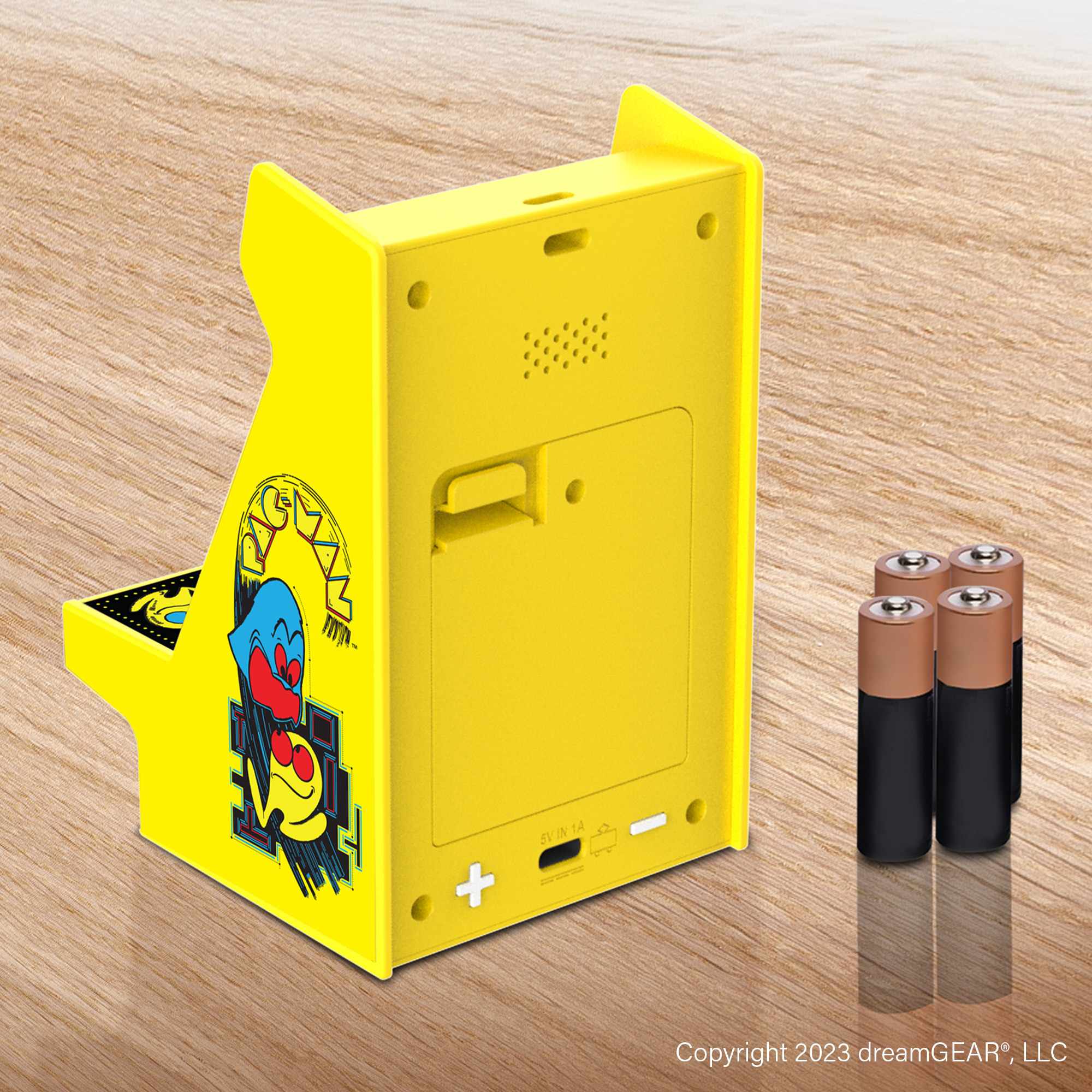 Sarı Pac-Man mini atari oyunu ve piller. Ahşap yüzey arka planı.