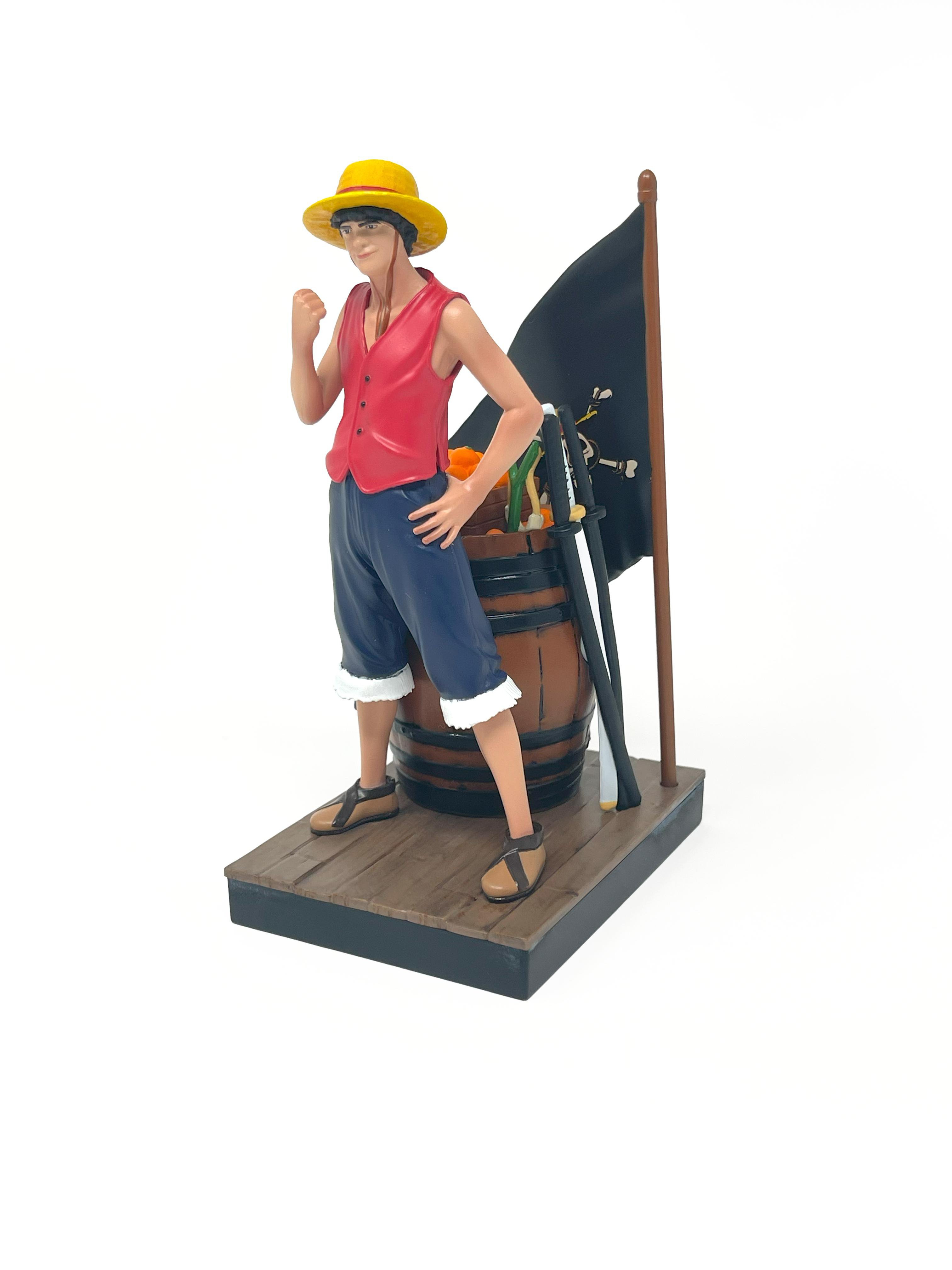 Luffy-Figur steht mit einem Fass, Orangen, einer Flagge und Schwertern. Posing, weißer Hintergrund.