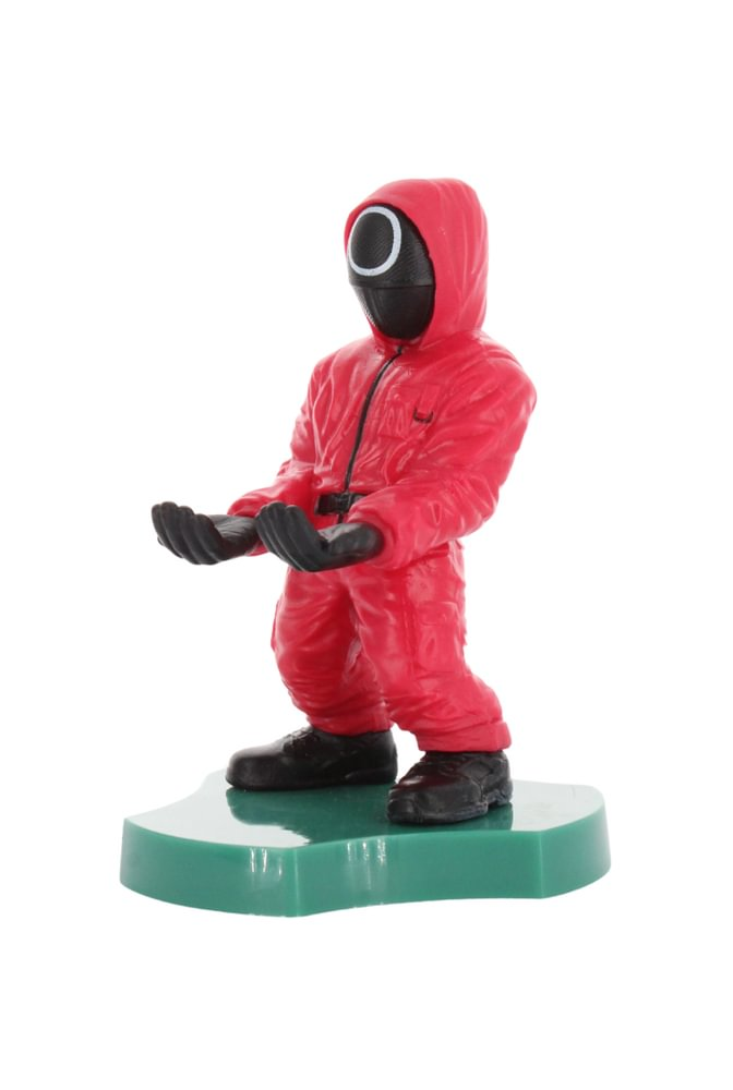 Eine Squid Game-Wächterfigur im roten Overall, schwarze Maske. Sie steht auf grüner Basis.