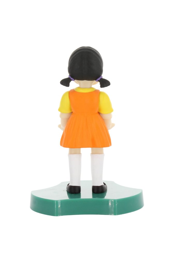 Rückansicht der Puppe. Sie trägt ein orangefarbenes Kleid mit gelben Ärmeln, weiße Socken und schwarze Schuhe. Weißer Hintergrund.