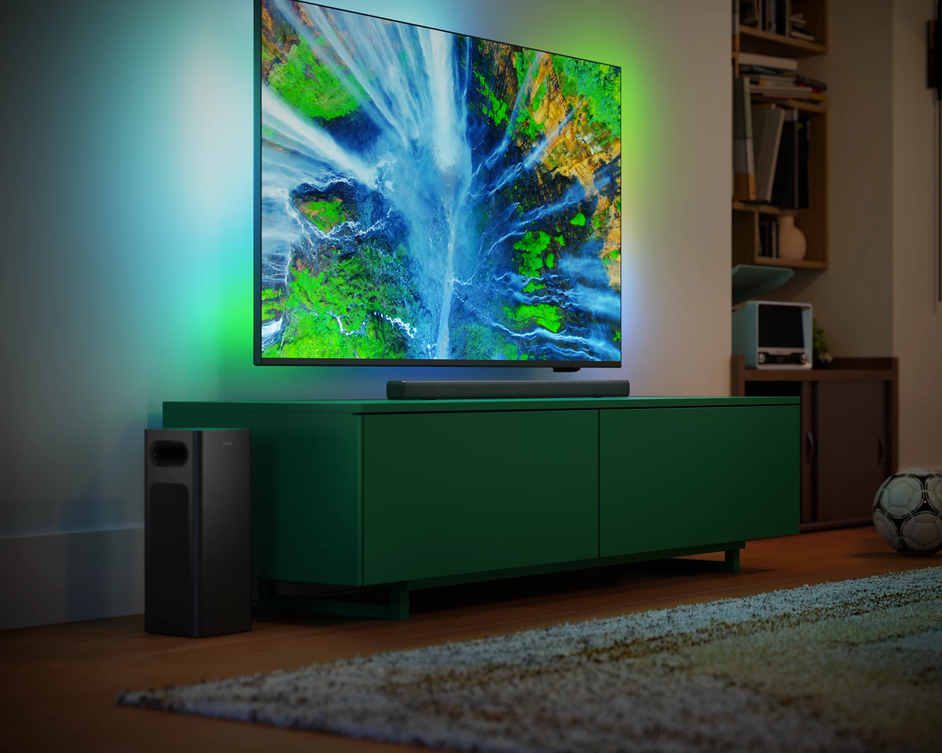TV con escena de cascada en mueble verde, subwoofer y balón de fútbol.