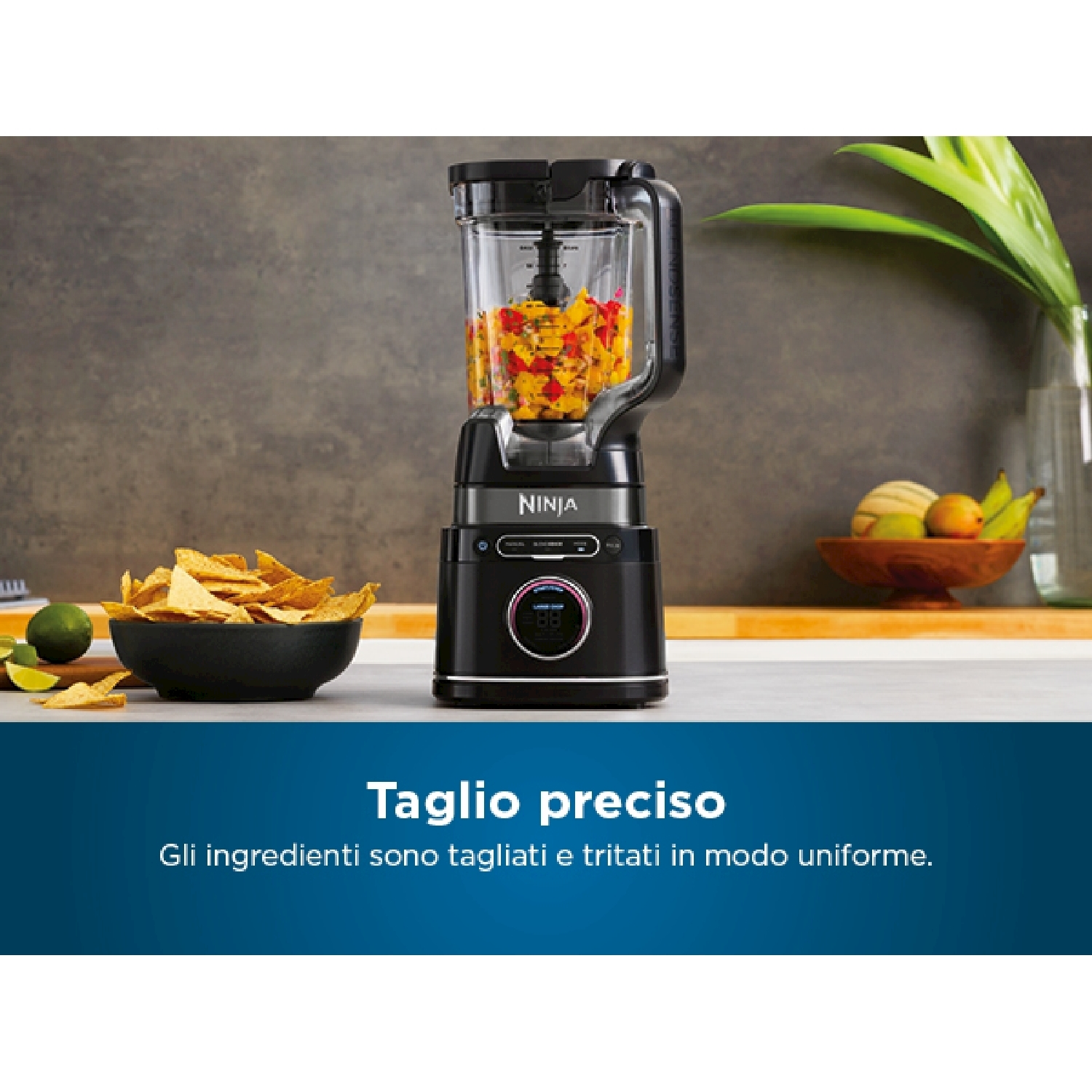 Un frullatore nero con cibo dentro, accanto a una ciotola di patatine e un lime.