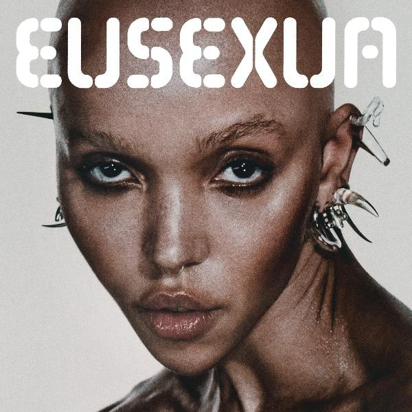Visage d'une femme chauve avec de grandes boucles d'oreilles. Le mot EUSEXUA est écrit en haut.