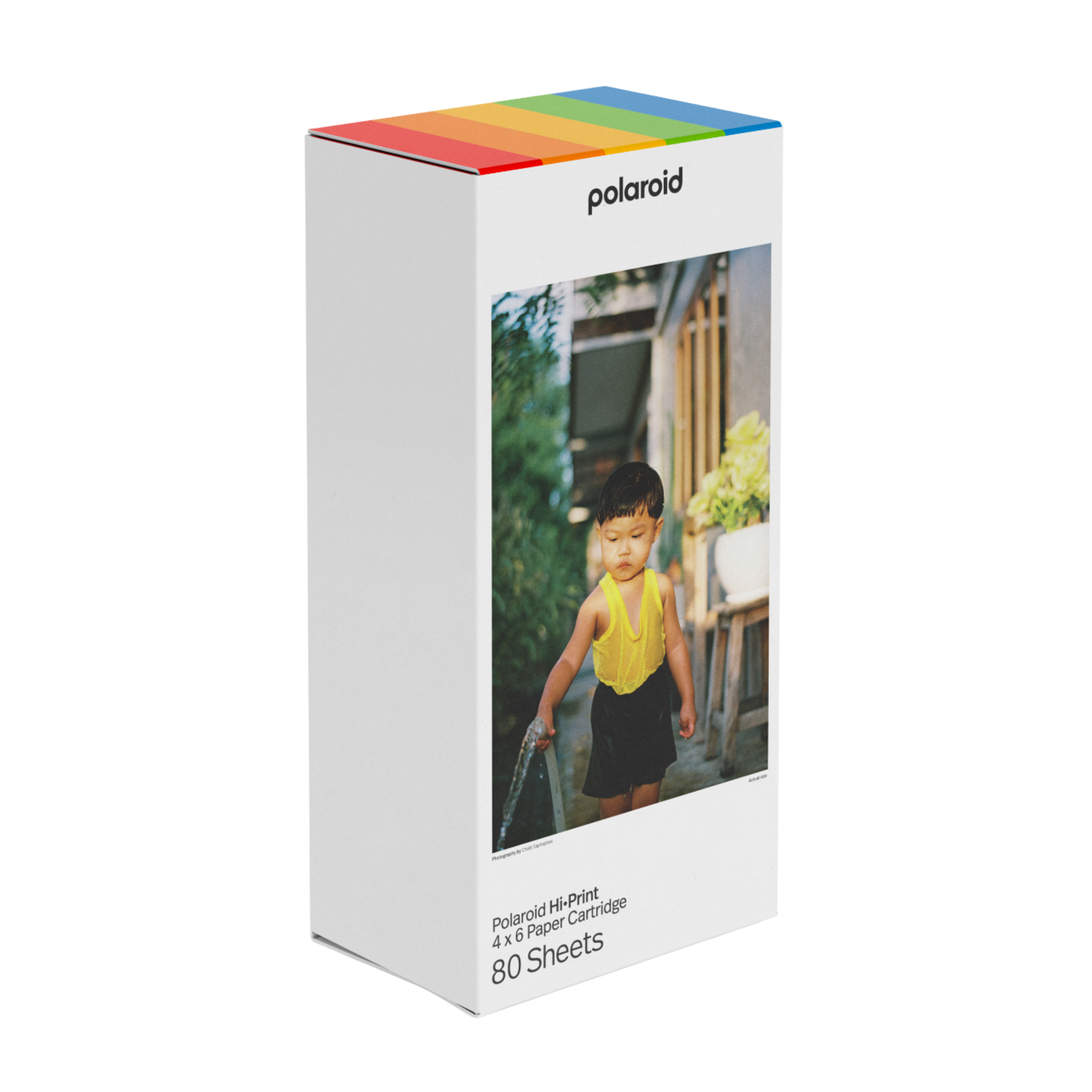 Une boîte Polaroid Hi-Print avec une photo d'un enfant jouant avec de l'eau. Des rayures arc-en-ciel en haut.