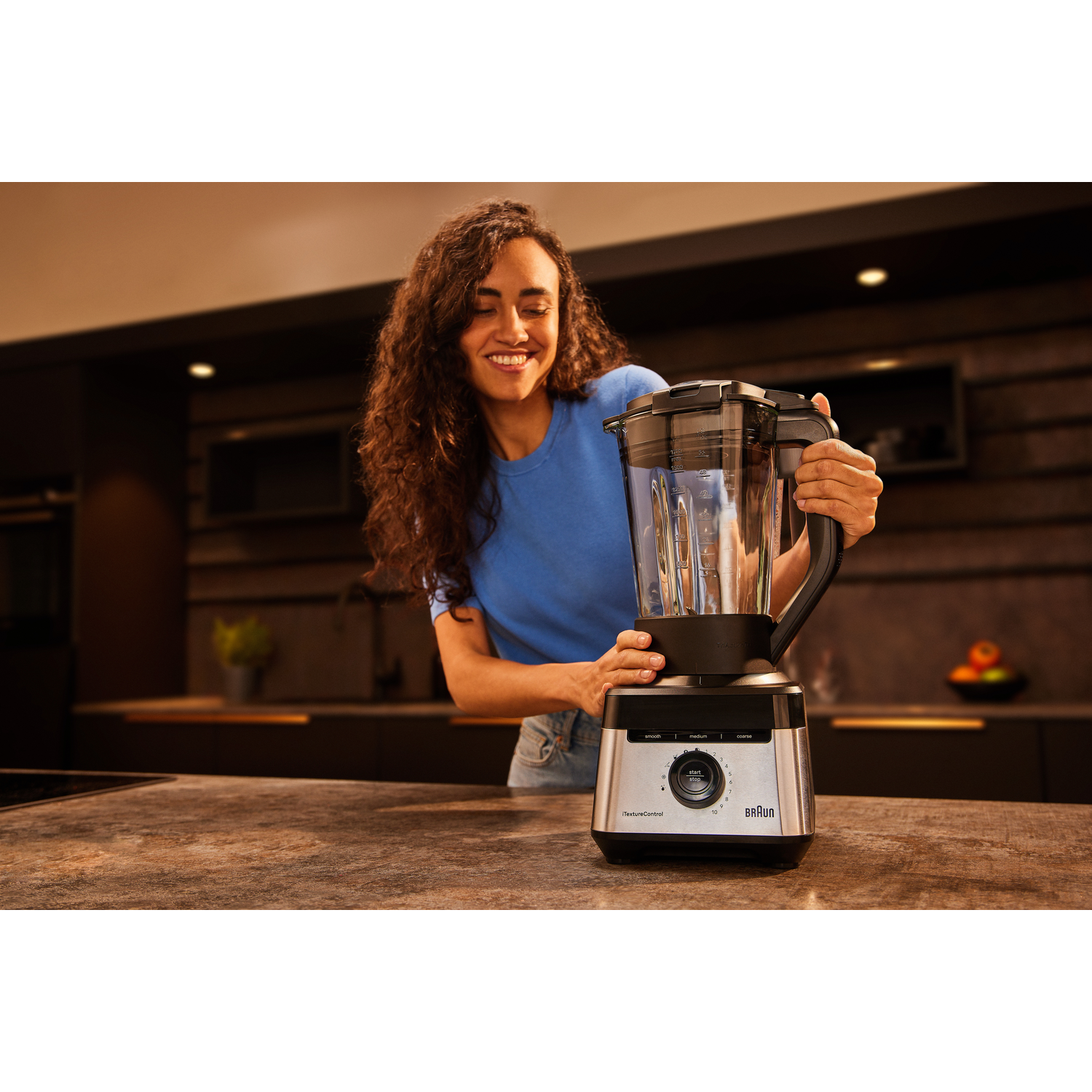 Woman is holding the blender in the kitchen.