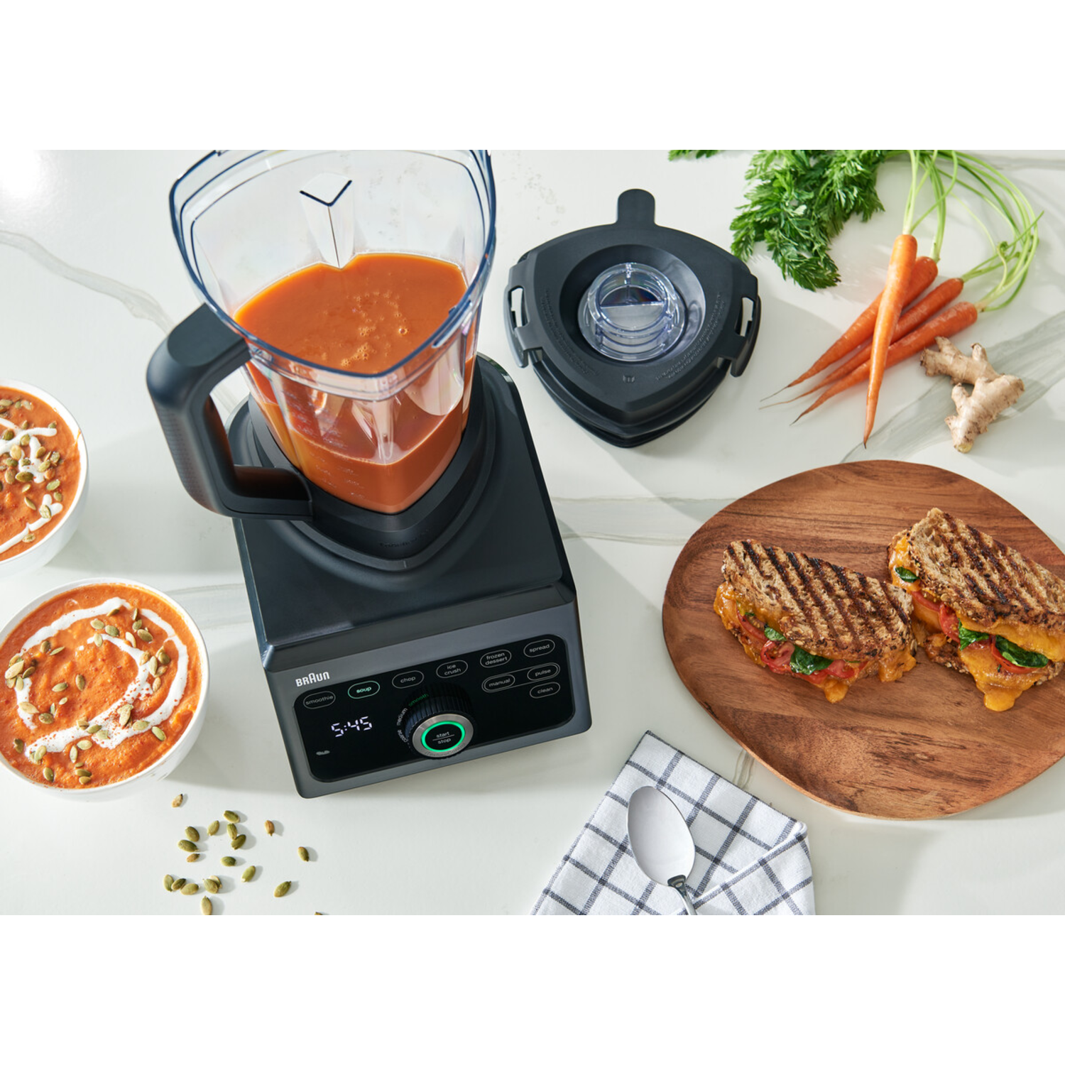 Blender with soup, carrot sticks and sandwiches.