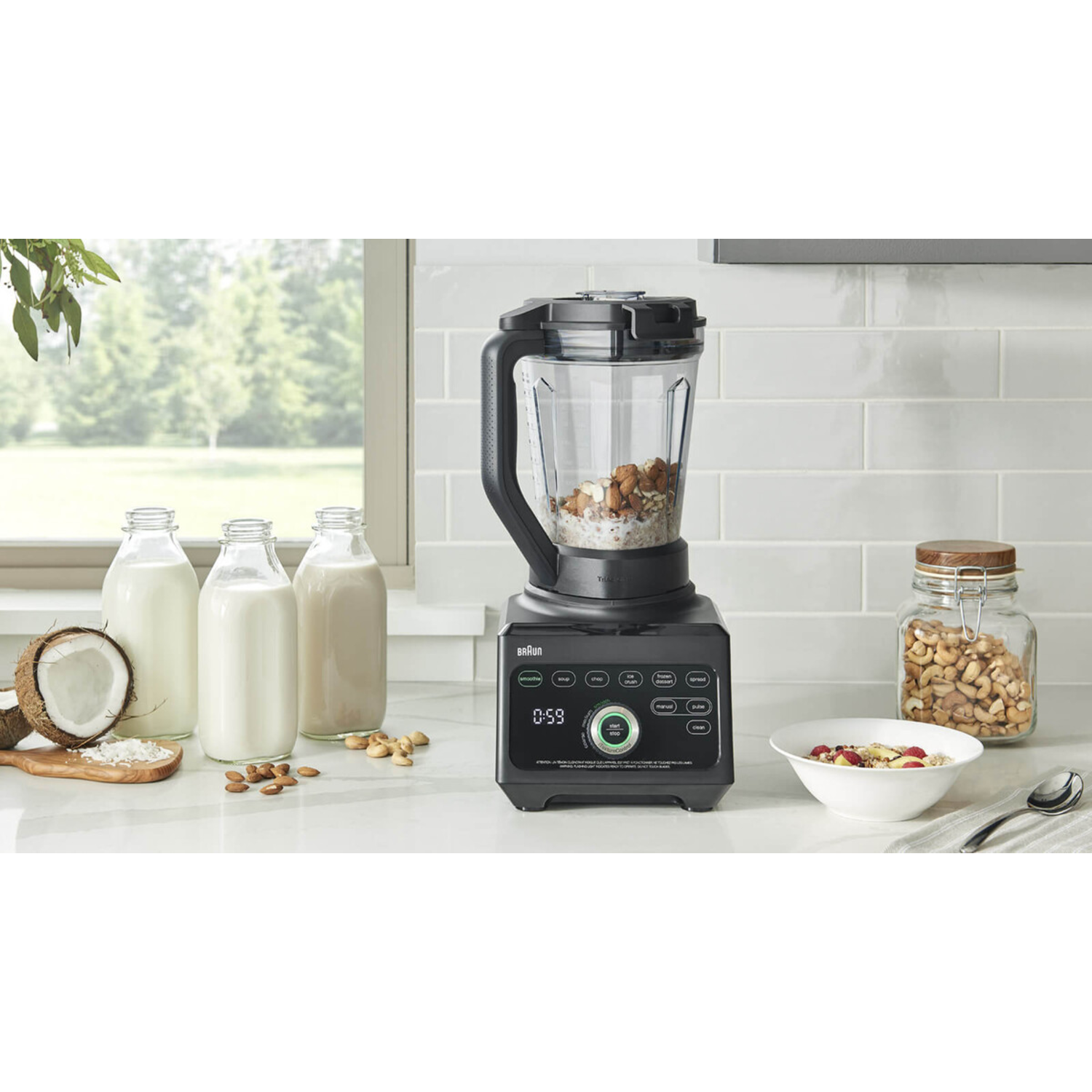 Blender with ingredients like almonds, oats, and coconut. Milk bottles and a bowl of oatmeal are also present.