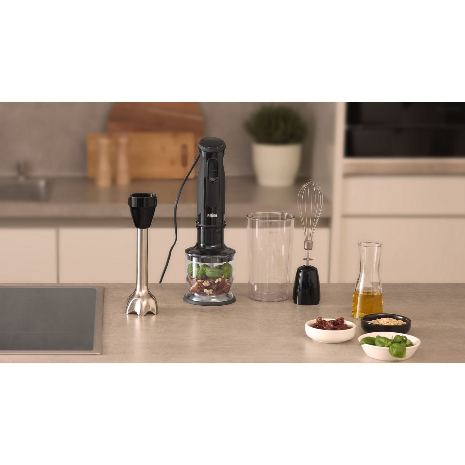 A Braun hand blender and accessories on a counter. Ingredients in bowls surround the blender.