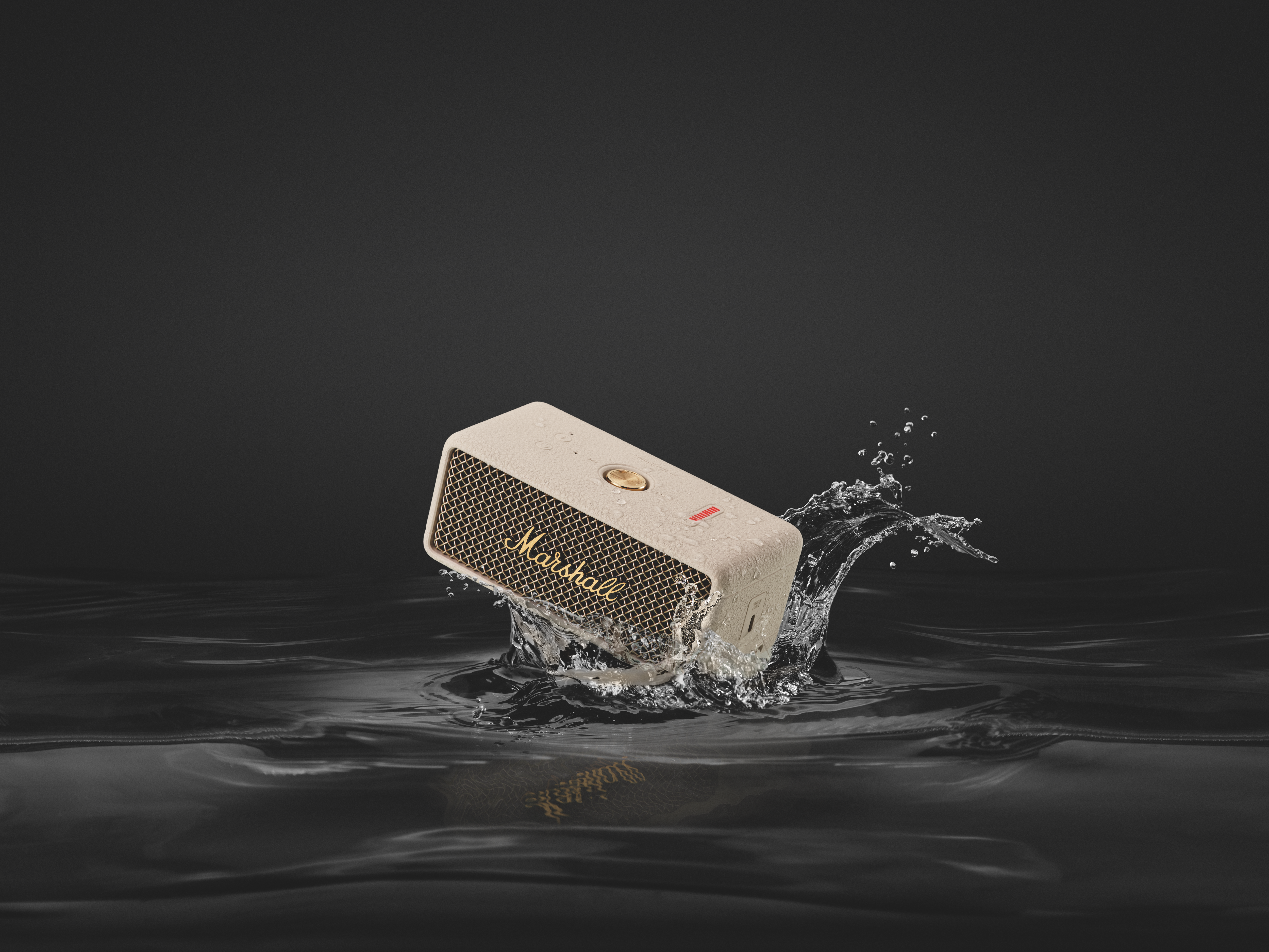 Ein beiger Marshall-Lautsprecher spritzt ins Wasser. Wasser spritzt um den Lautsprecher herum.
