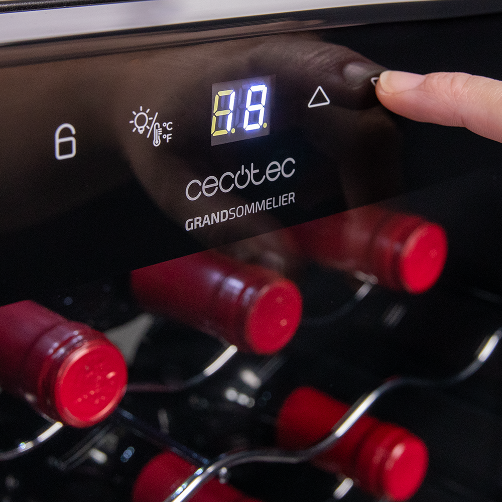 Primer plano del panel de control de una vinoteca. Un dedo toca el botón de subir.