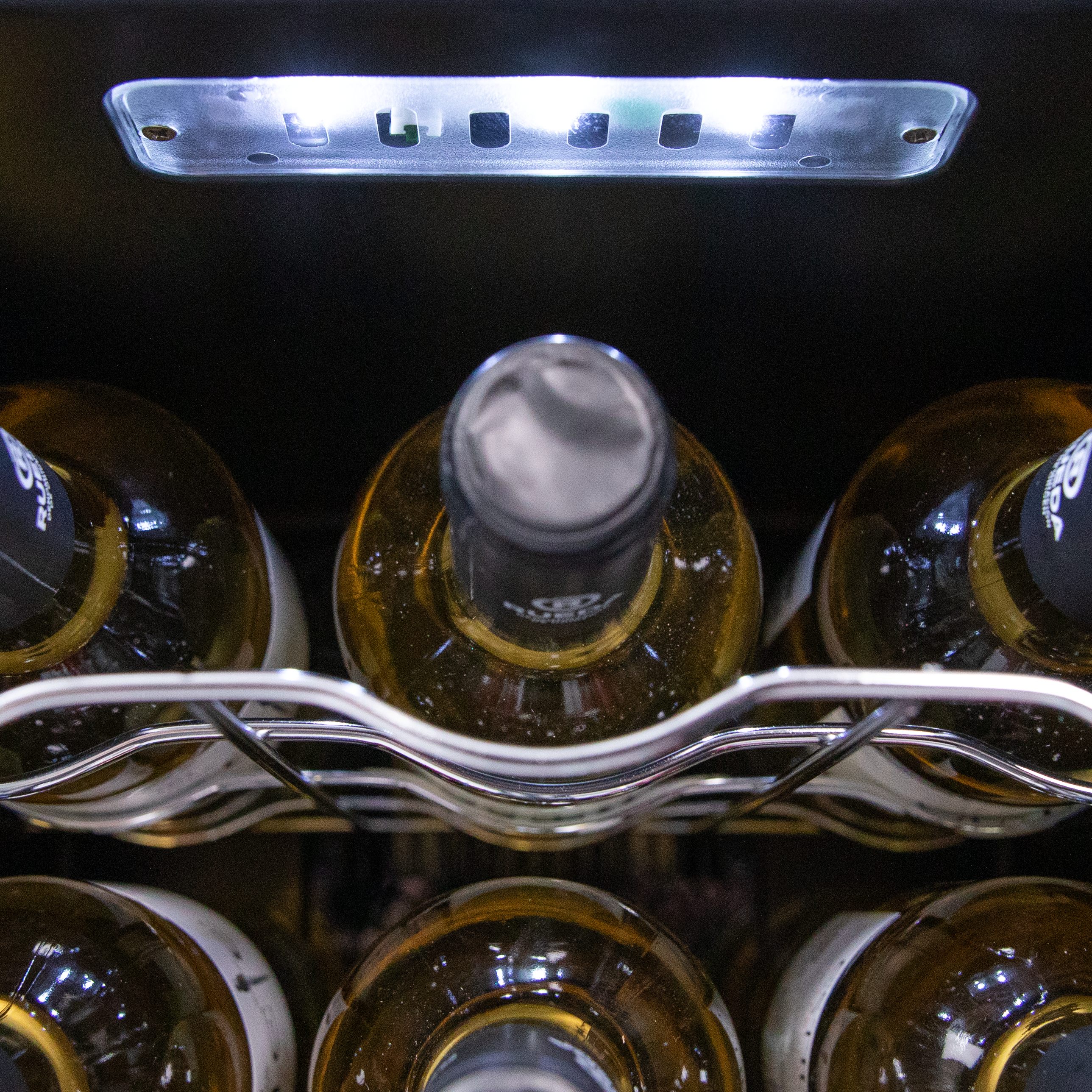Primer plano del interior de una vinoteca. Se ven botellas de vino blanco bajo una luz.