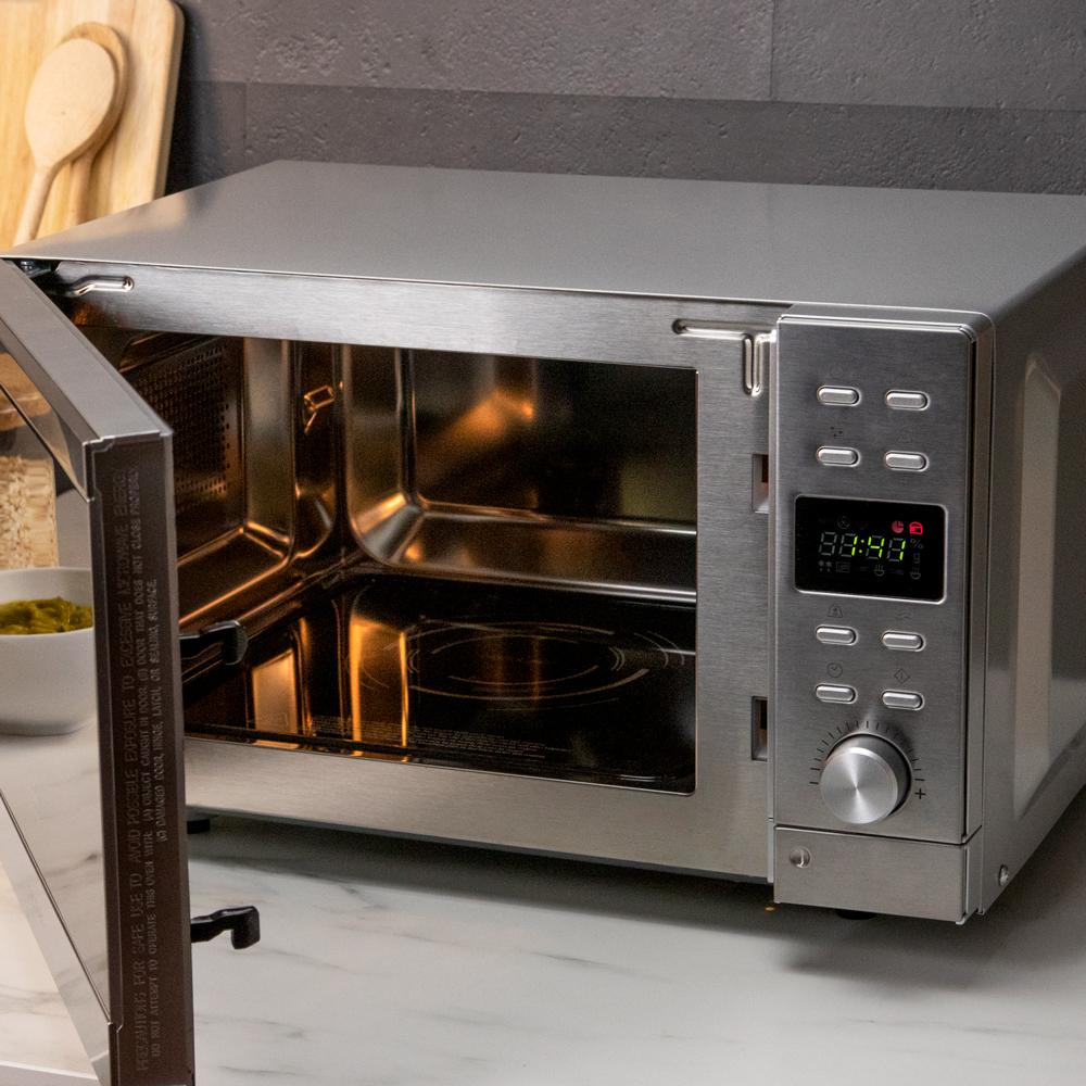 Un horno microondas plateado con la puerta abierta, mostrando el interior y el panel de control.