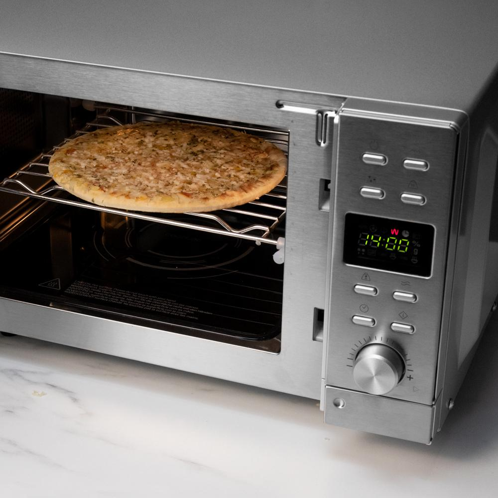 Una pizza redonda está dentro de un horno microondas plateado.