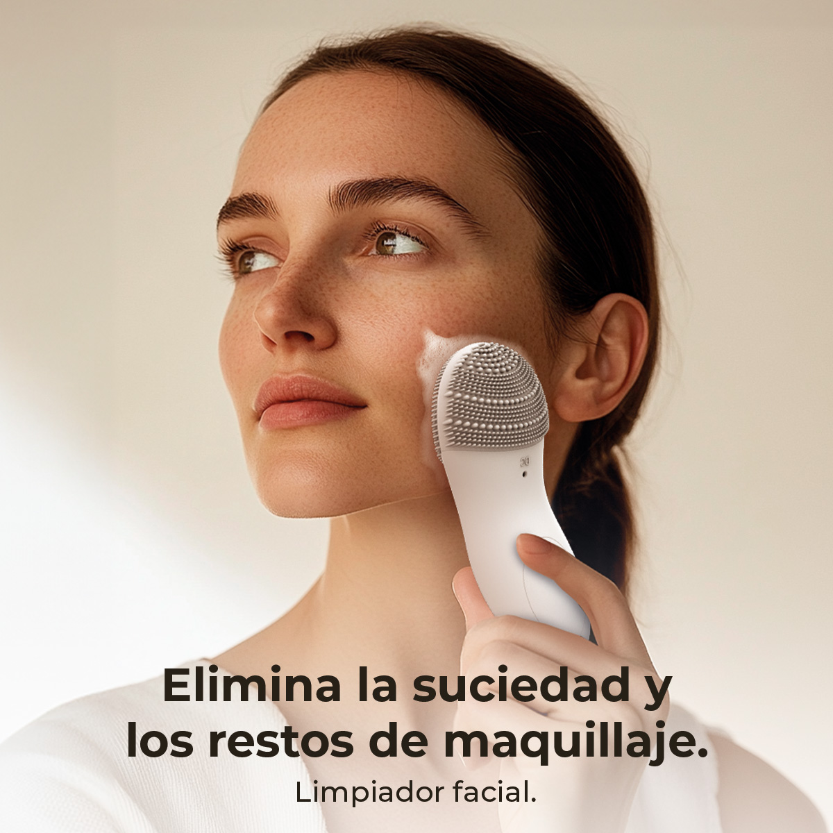 Una mujer usando un limpiador facial en su rostro. El texto en la imagen dice: 'Elimina la suciedad y los restos de maquillaje'.