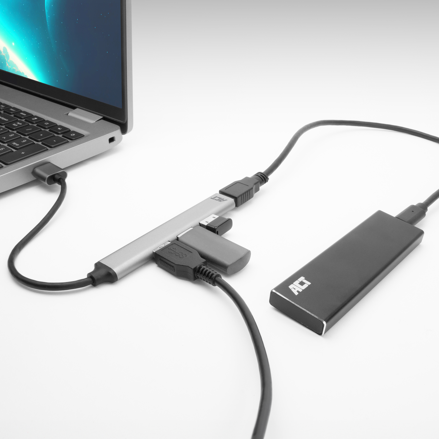 Laptop connected to a silver USB hub, black external hard drive nearby.