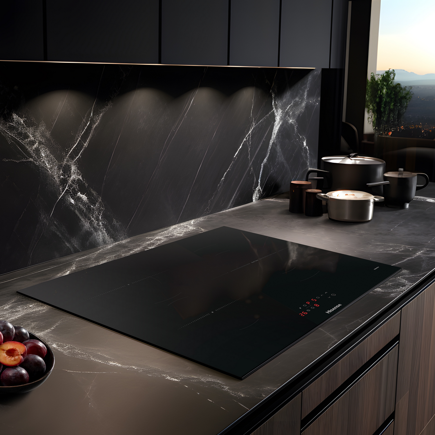 Placa de inducción negra sobre encimera de mármol. Cocina negra y marrón con fruta.
