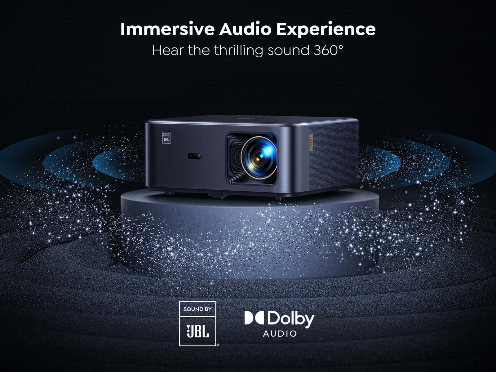 Bir kaide üzerinde siyah bir projektör. Mavi ses dalgaları yayılır. Aşağıda JBL ve Dolby logoları var.