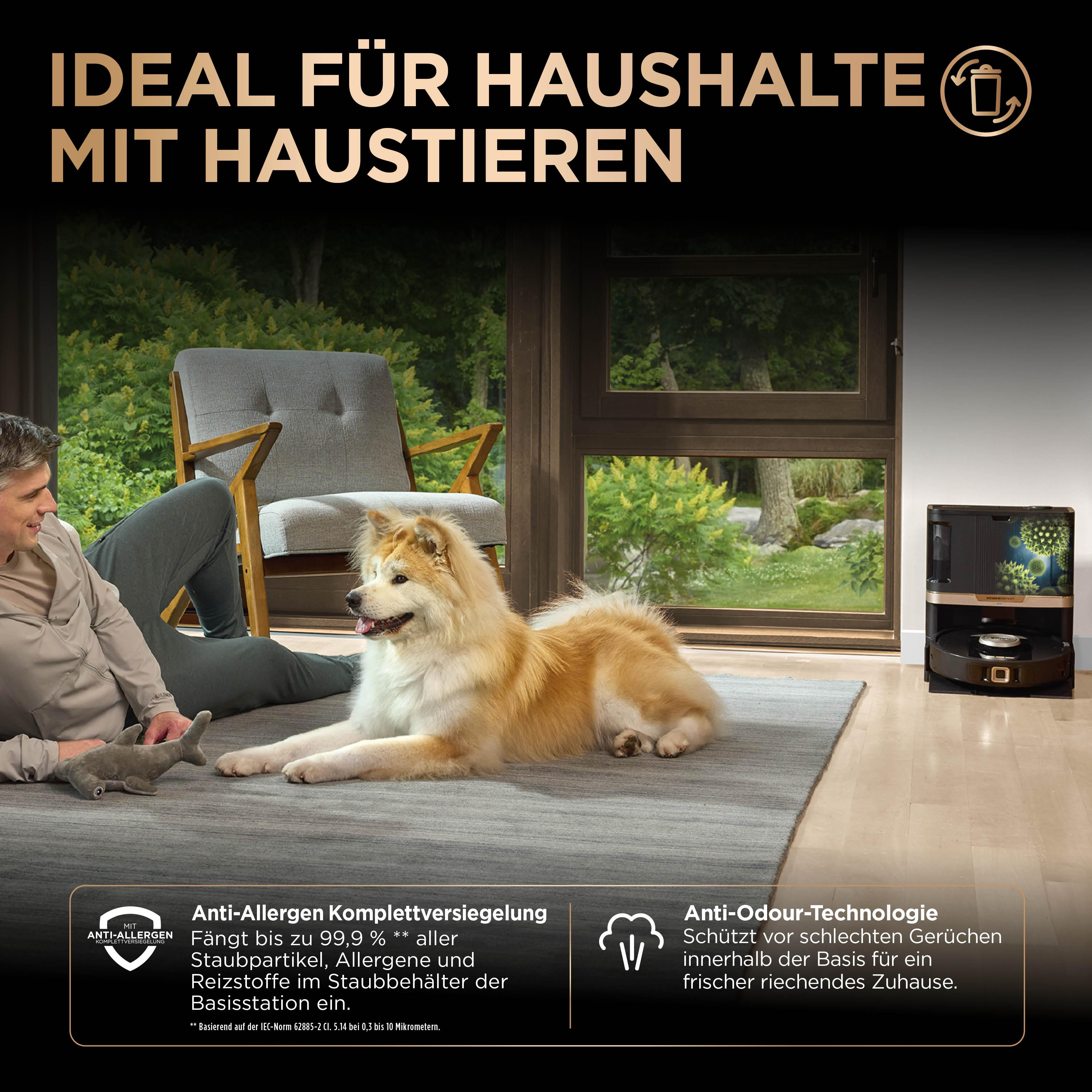 Ein Hund liegt auf einem Teppich neben einem Mann. Ein Roboter-Staubsauger ist im Hintergrund.