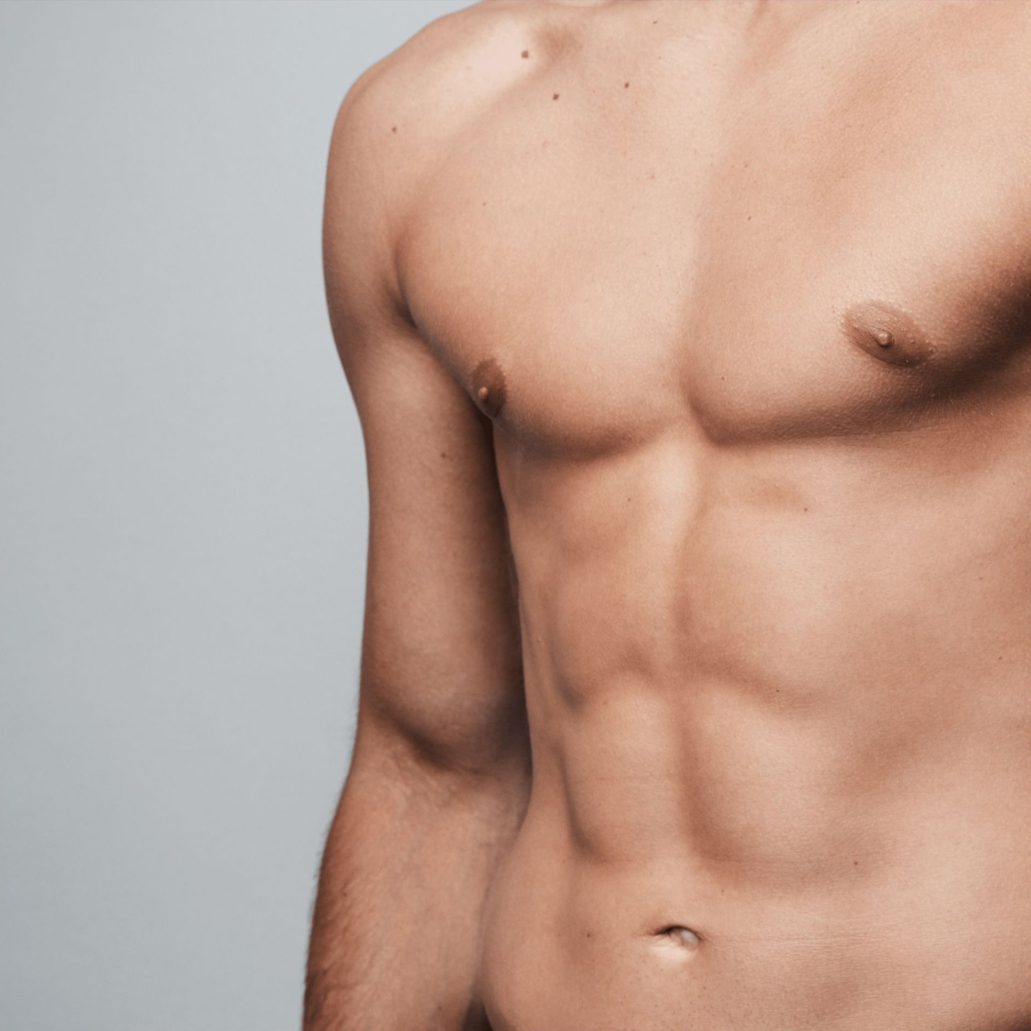 Primo piano del torso di un uomo. Pelle chiara, muscoli addominali visibili e sfondo grigio chiaro.