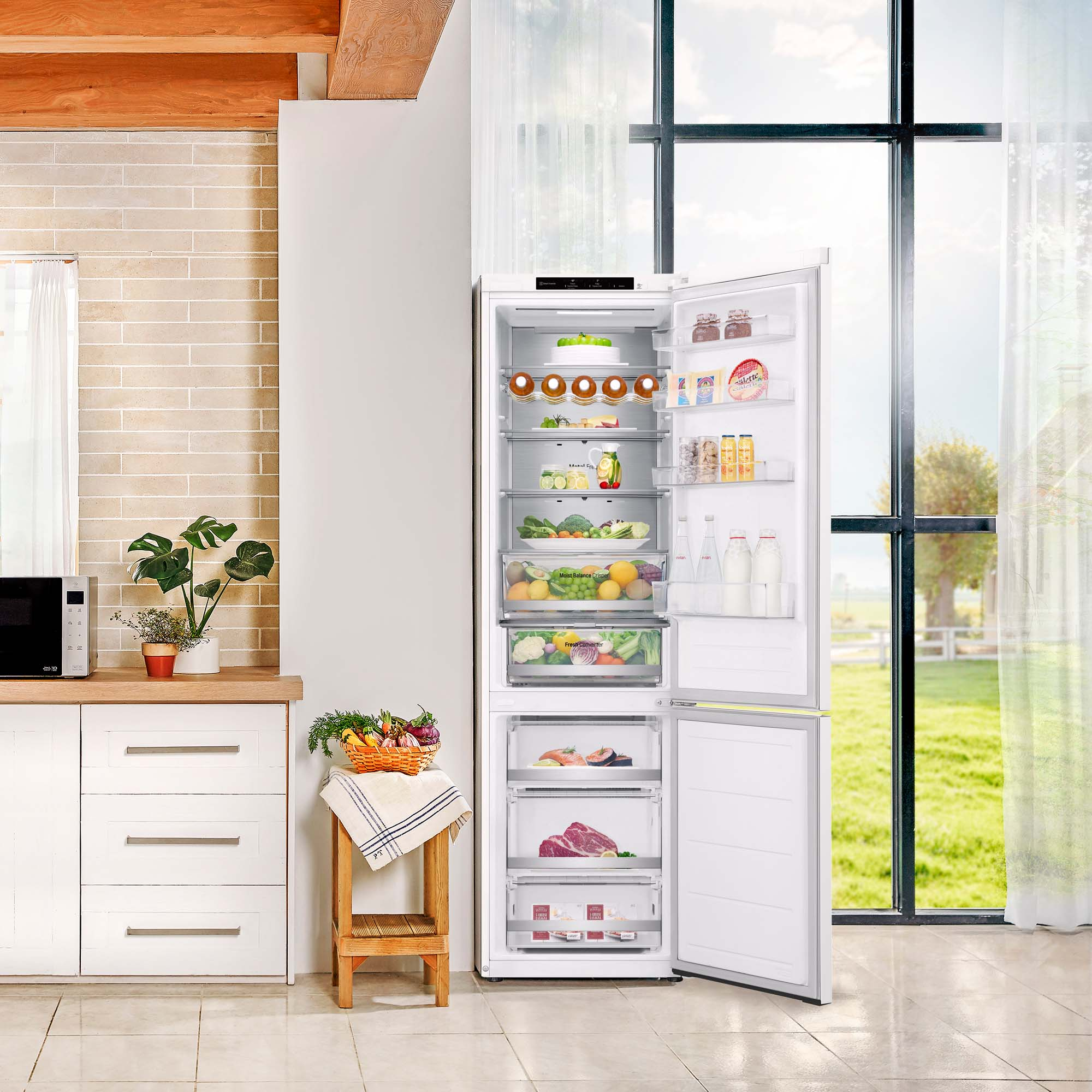Refrigerador blanco con puertas abiertas, lleno de comida. Entorno de cocina, ventana al fondo.