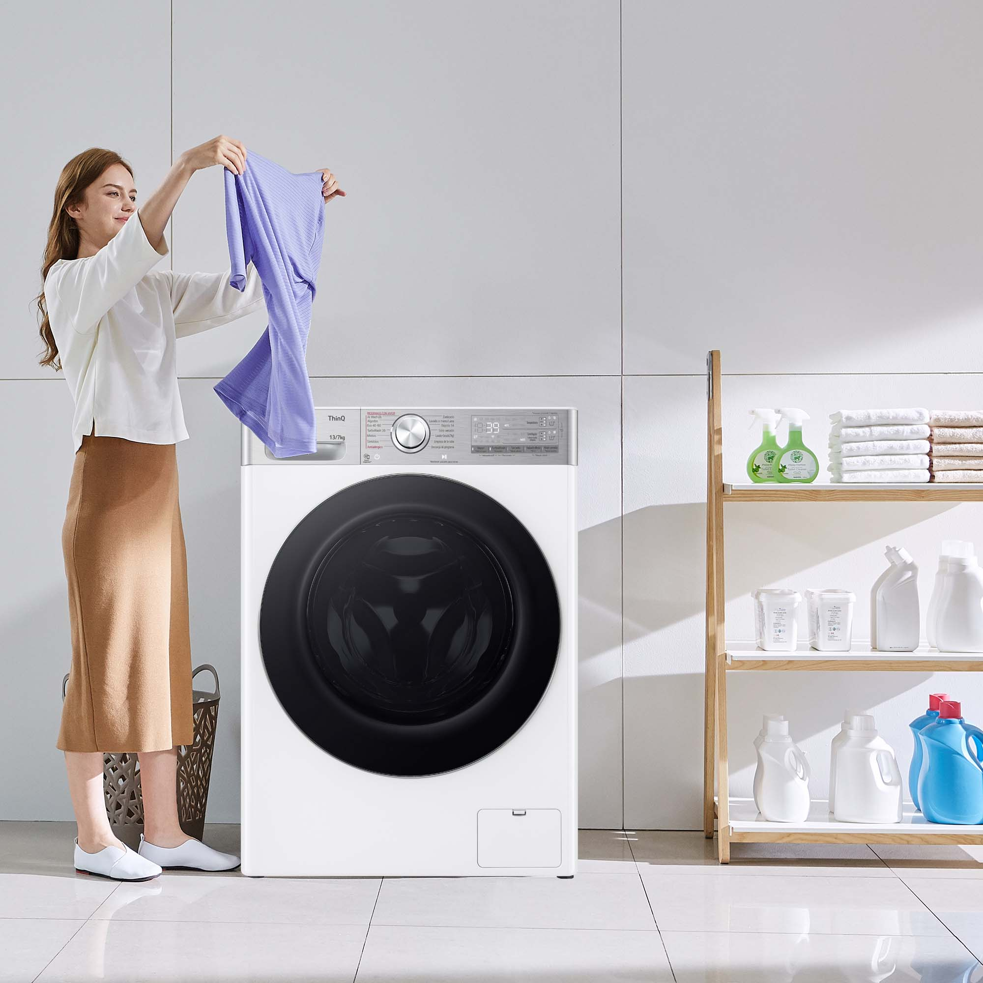 Mujer sosteniendo ropa morada sobre lavadora LG blanca.