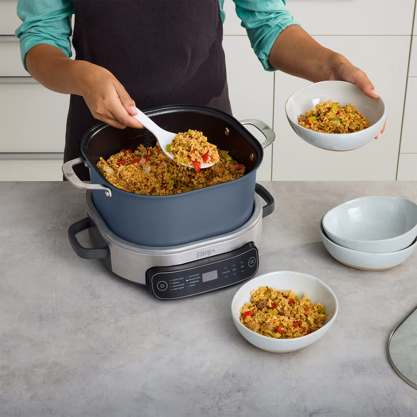 Essen wird aus einem Kochtopf serviert. Schalen mit Essen stehen ebenfalls auf der Theke, mit einer Kochmaschine.