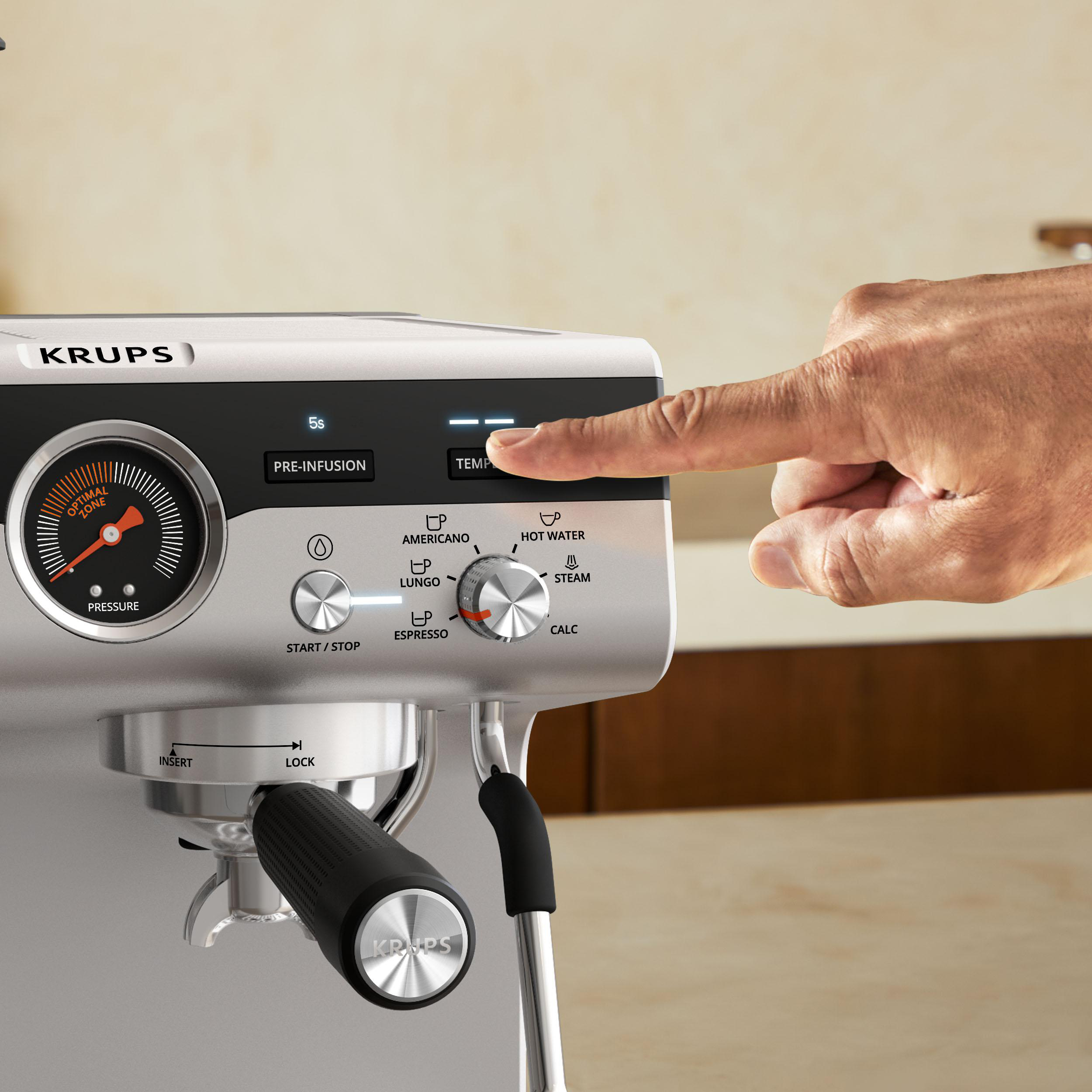 Eine Hand drückt die Temperaturtaste auf einer Krups Espressomaschine, Nahaufnahme.