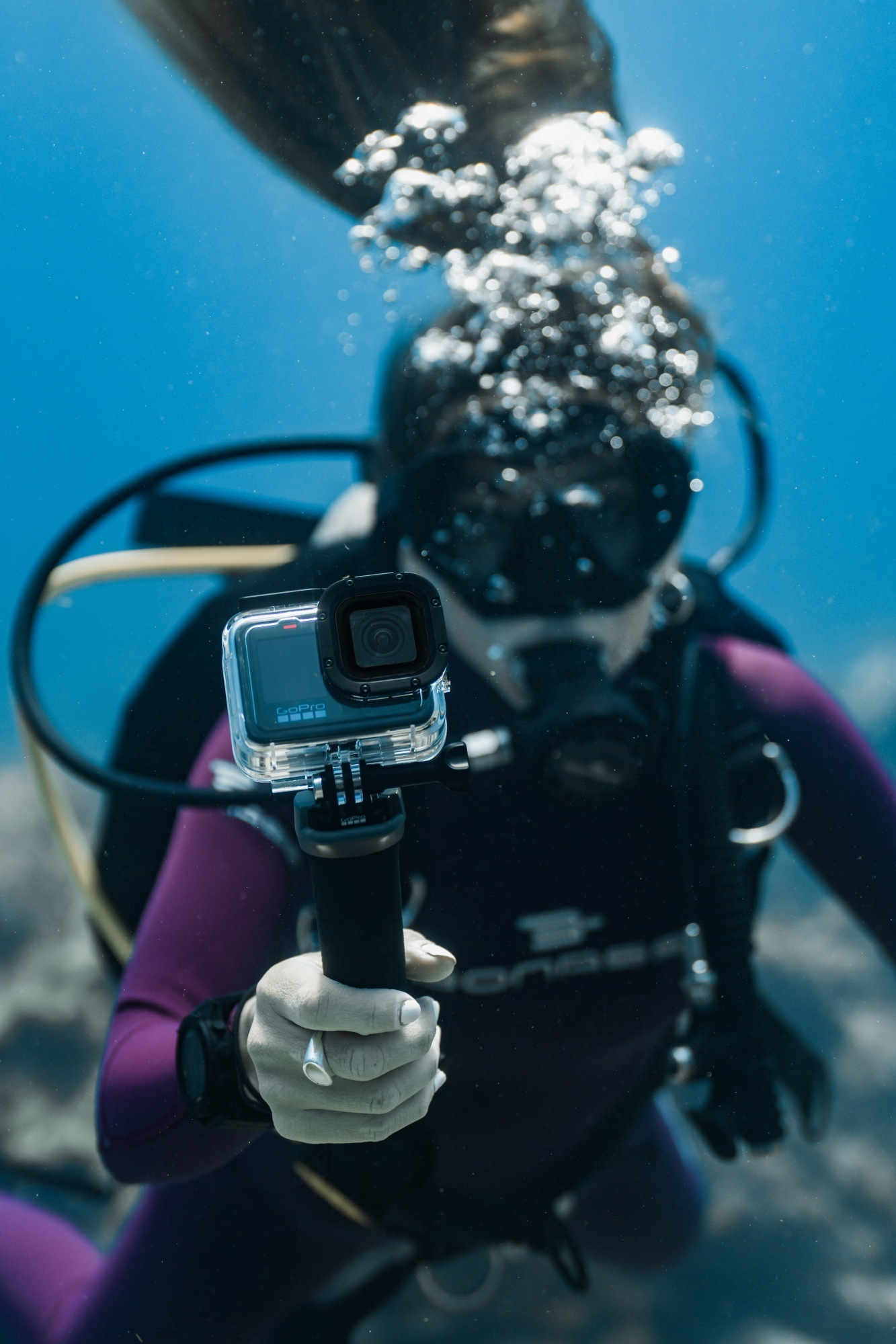 Ein Taucher unter Wasser mit einer GoPro und einem lila Anzug.