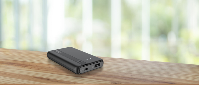Eine schwarze Powerbank auf einer Holzoberfläche, verschwommener Hintergrund.