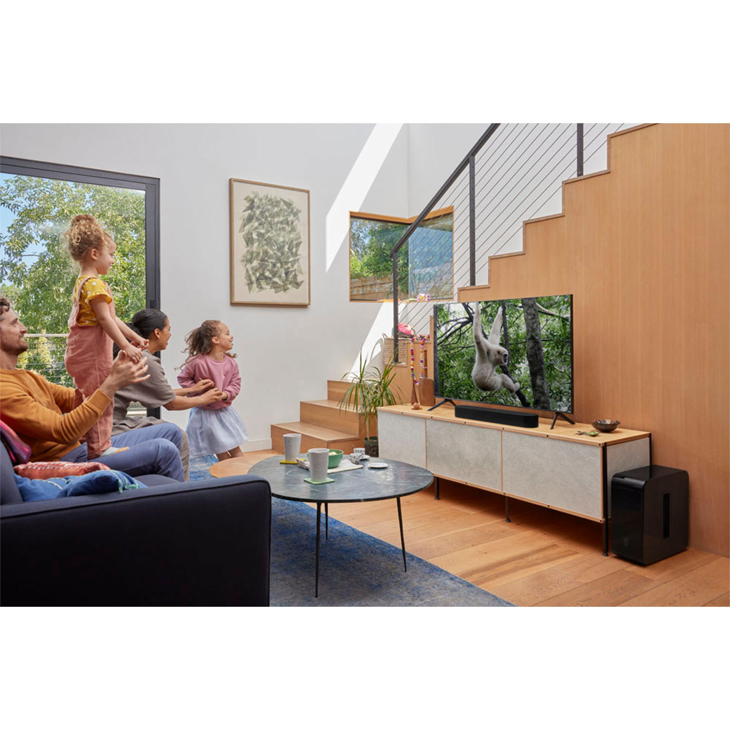 Famiglia che guarda la TV con una scimmia sullo schermo. Soggiorno moderno con scale.