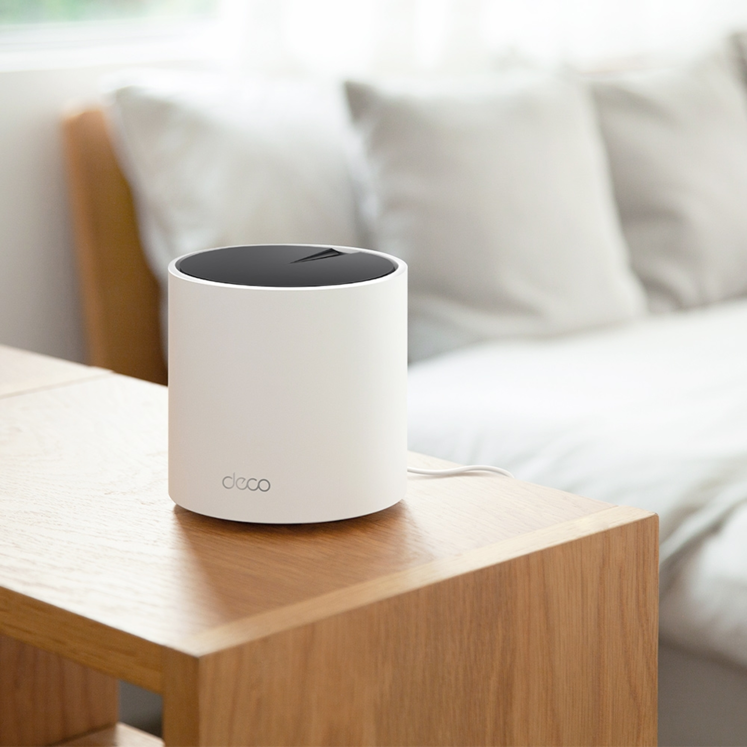 Routeur WiFi blanc et noir sur une table en bois. Lit en arrière-plan.
