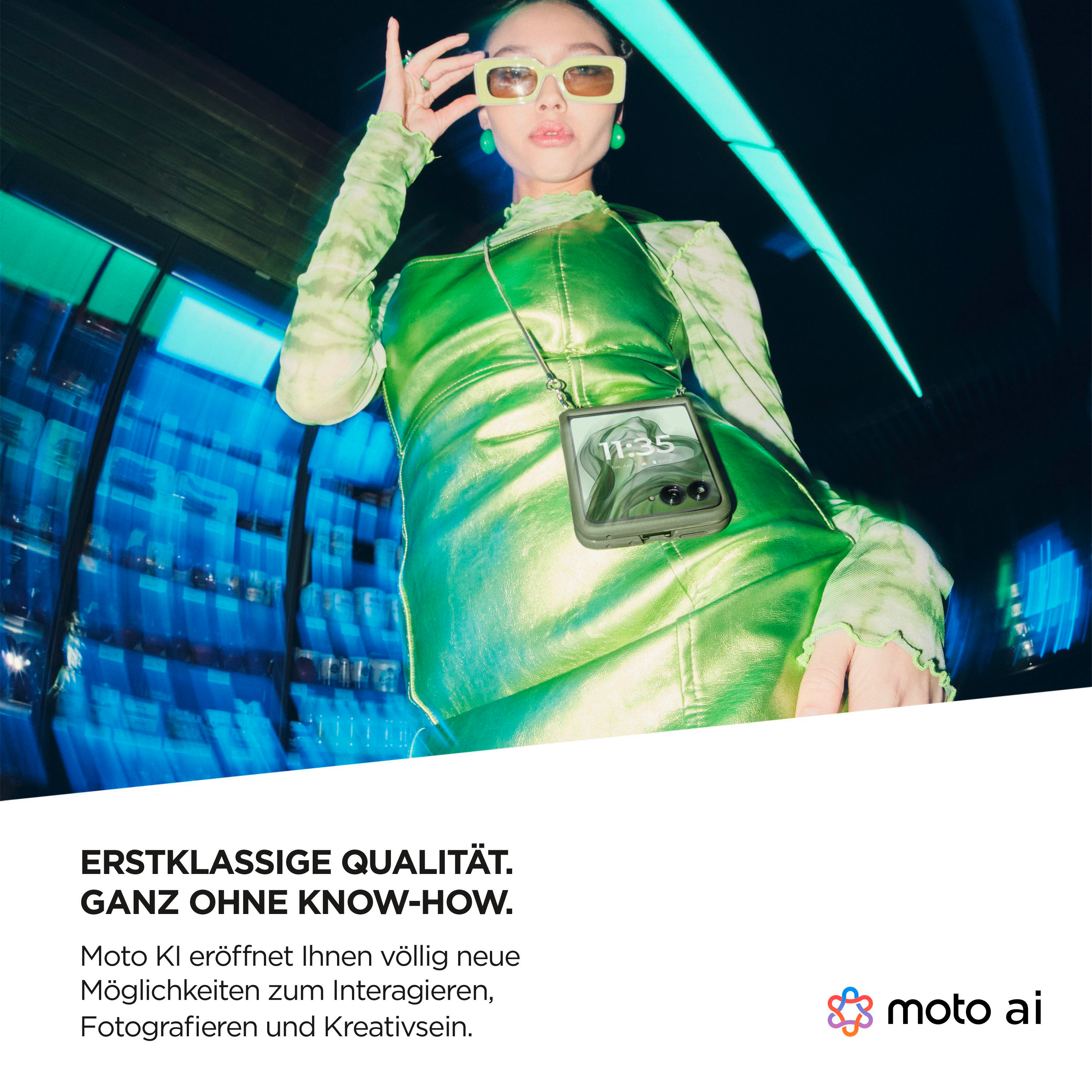 Eine Frau in Grün hält ein grünes faltbares Telefon. Das Telefon hat ein Motorola-Logo und die Uhrzeit auf dem Bildschirm.