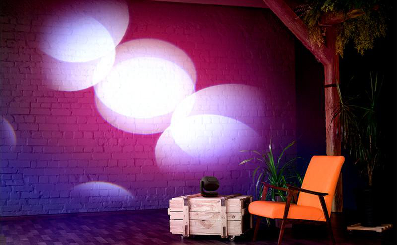 Innenaufnahme mit Holzkiste, Lichtern und einem orangefarbenen Stuhl.