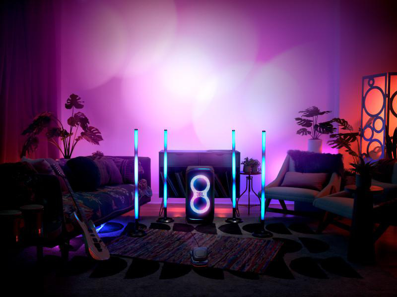 Wohnzimmer mit farbenfroher Beleuchtung. Lautsprecher und Lichter im Raum. Pflanzen und Gitarre.