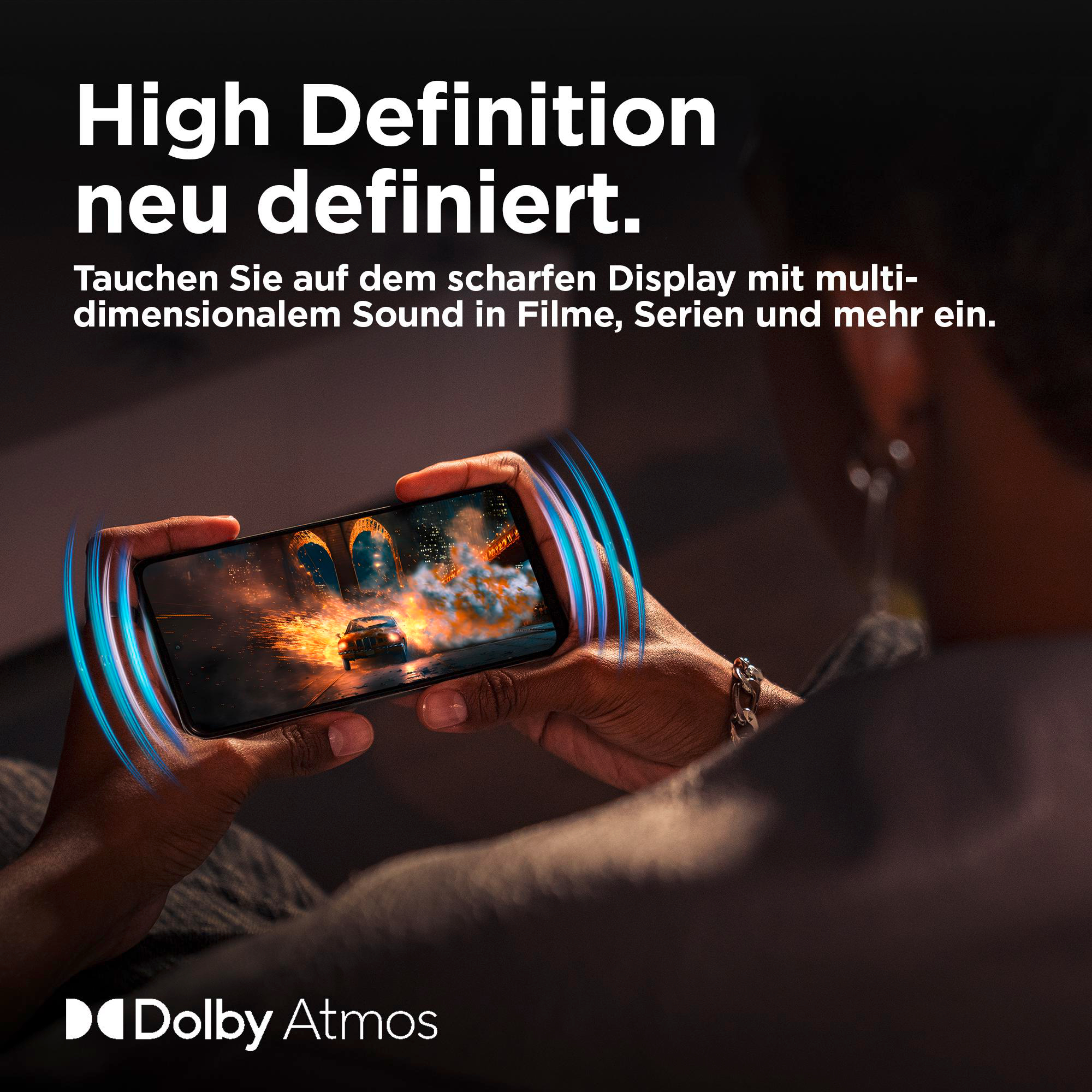 Person hält Telefon mit Autorennszene. Text über High Definition oben, Dolby Atmos Logo unten.