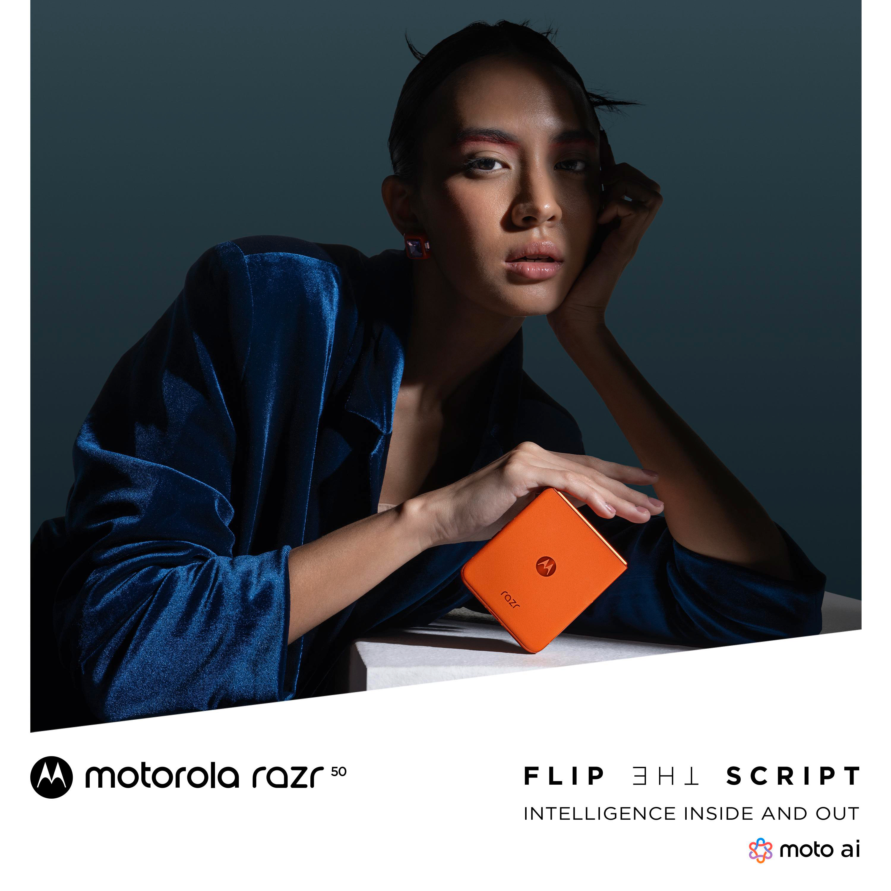 Eine Frau hält ein oranges Telefon in einem dunklen Studio in der Nähe ihres Gesichts.