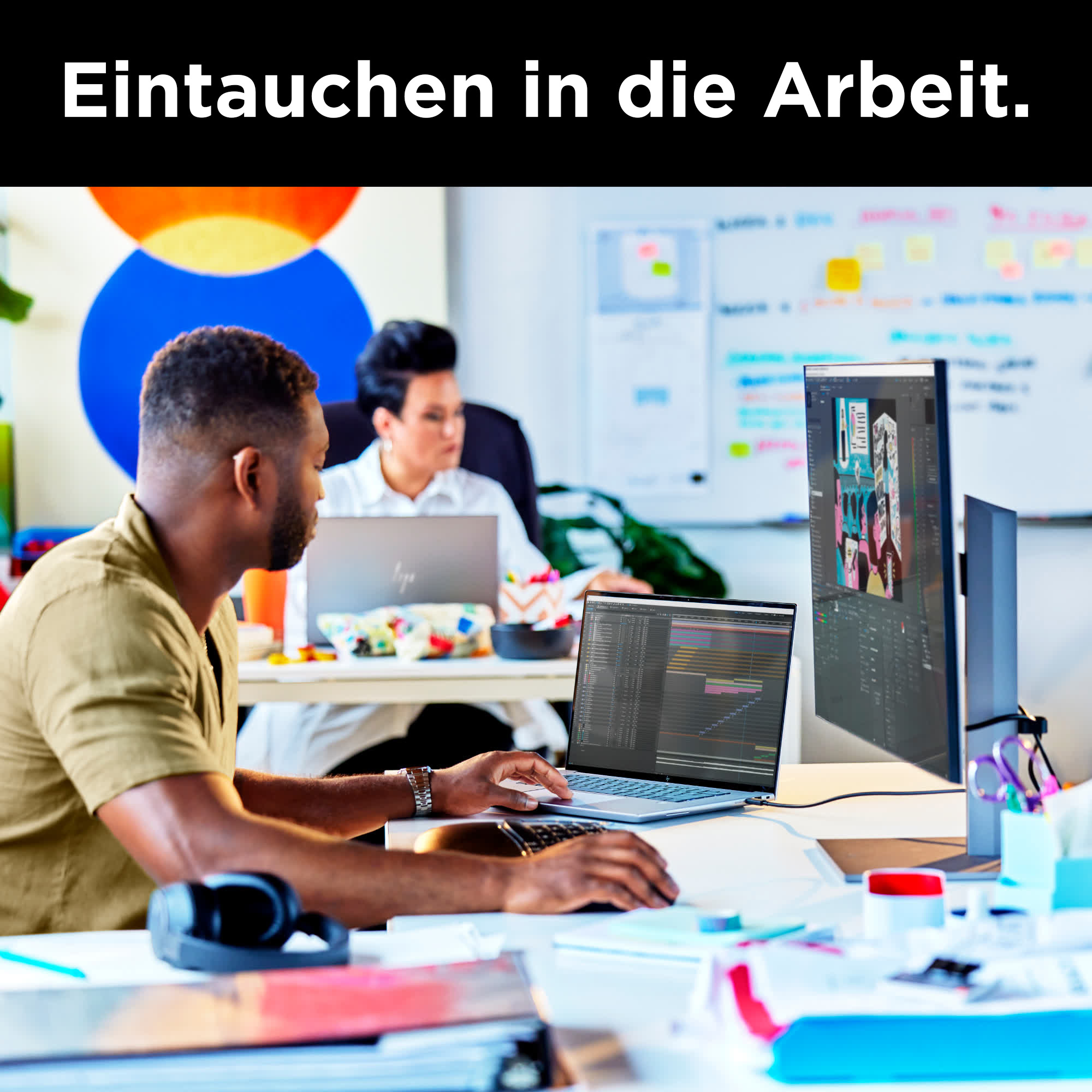 Eine Person, die in einer Büroumgebung einen Laptop mit einem großen Bildschirmmonitor benutzt.