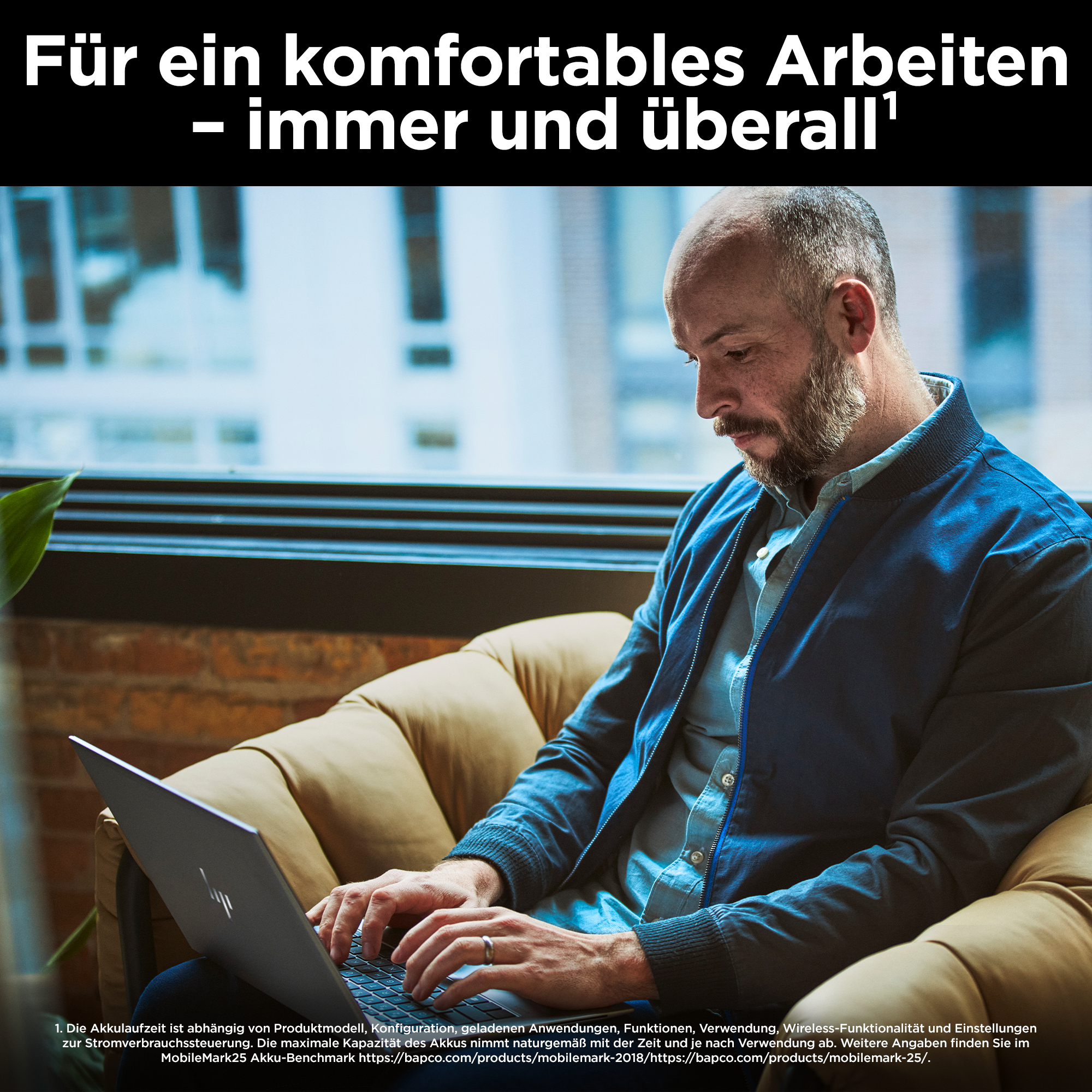 Ein Mann arbeitet auf einem Laptop, während er auf einem Sofa sitzt. Links im Bild ist eine Pflanze.