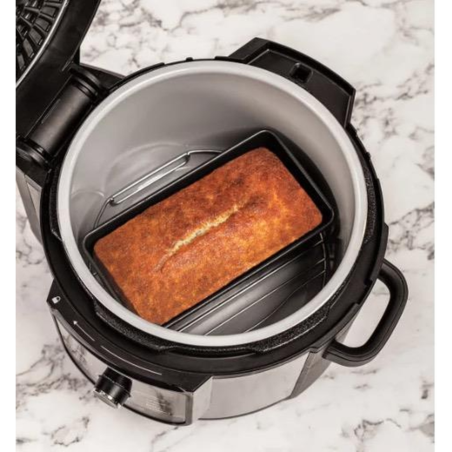 Un Ninja Foodi aperto. Una pagnotta di pane cotta al forno si trova in una teglia all'interno.