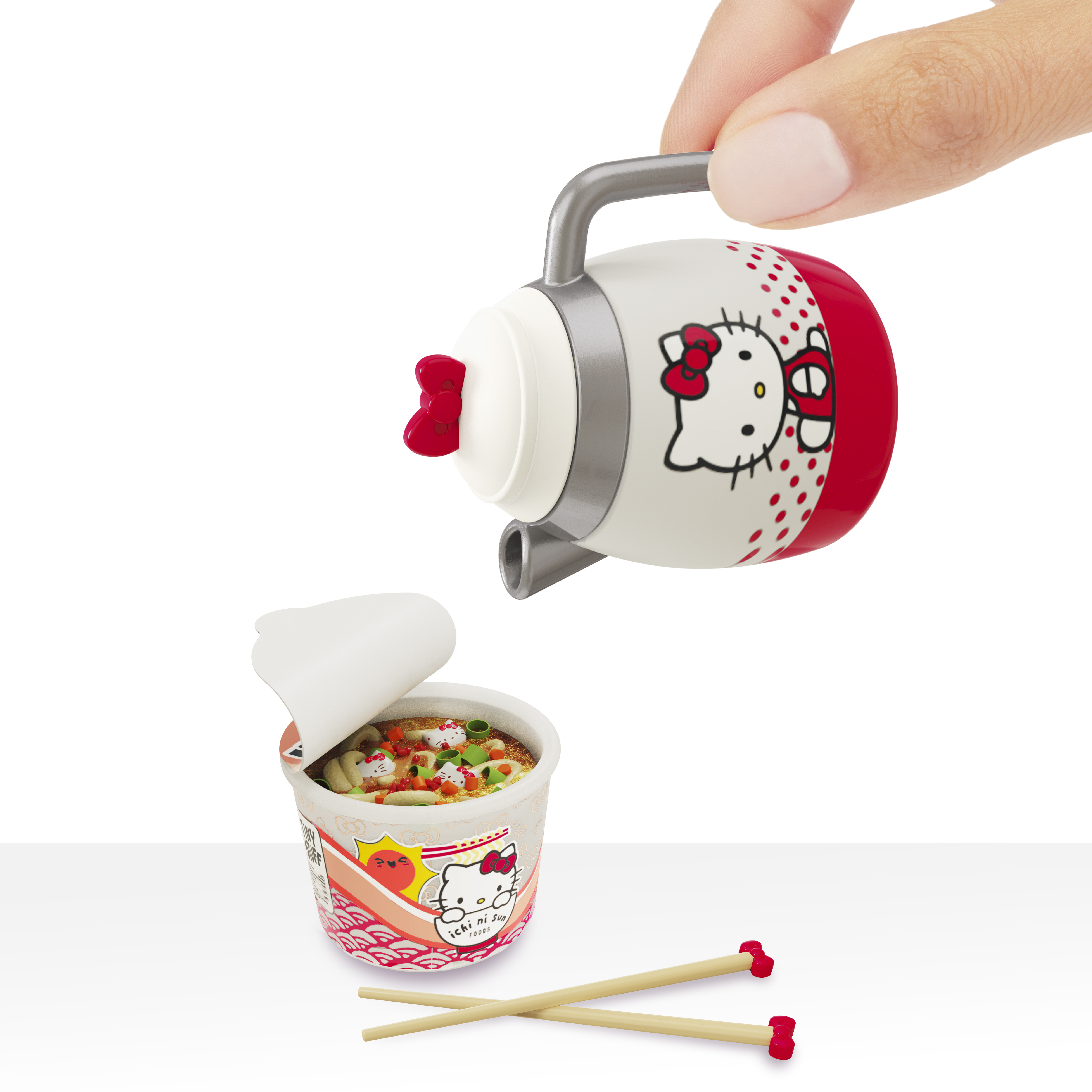 Eine Hand, die Soße aus einem Hello Kitty-Behälter in eine Tasse Nudeln gießt.