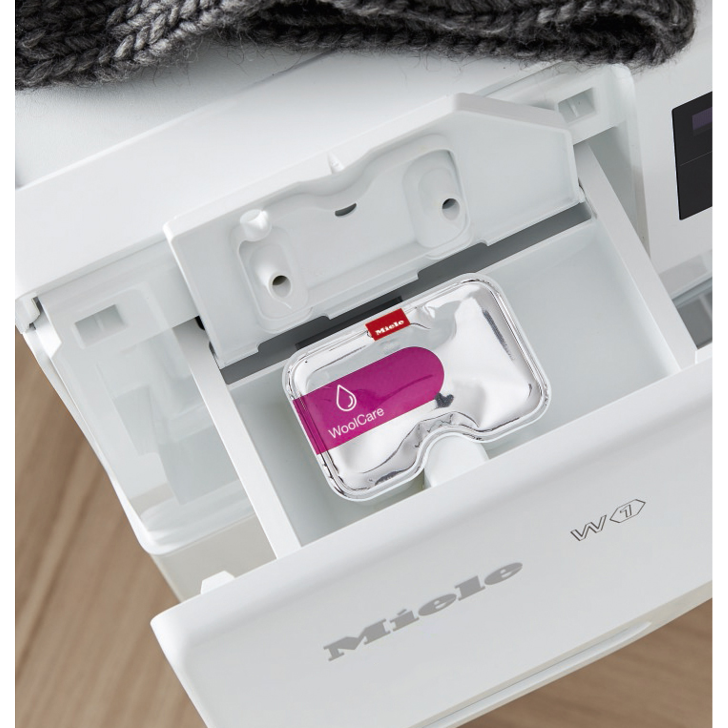 Washing machine drawer with a Miele WoolCare tablet inside.
