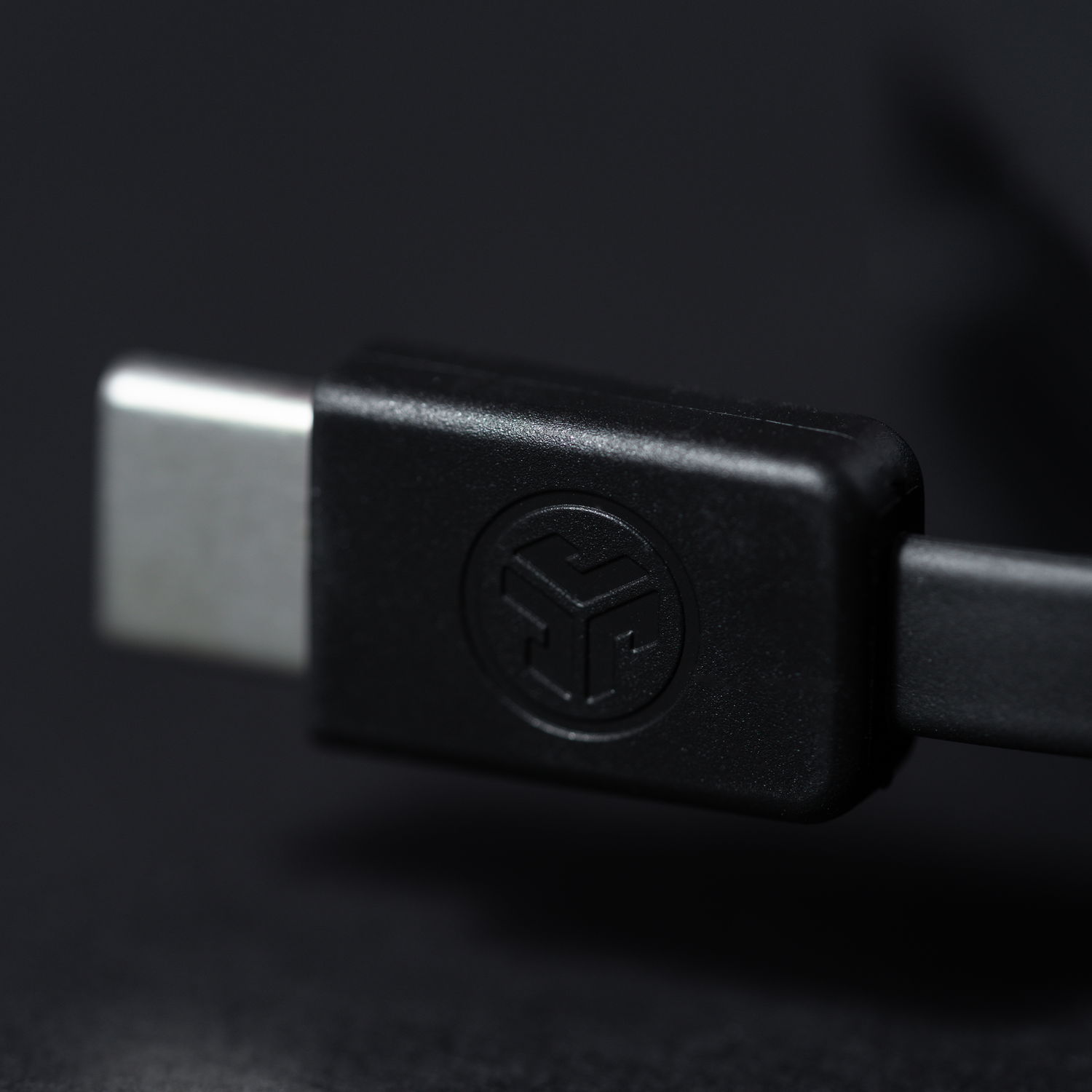 Close-up of a black USB-C connector with a logo on a dark background.