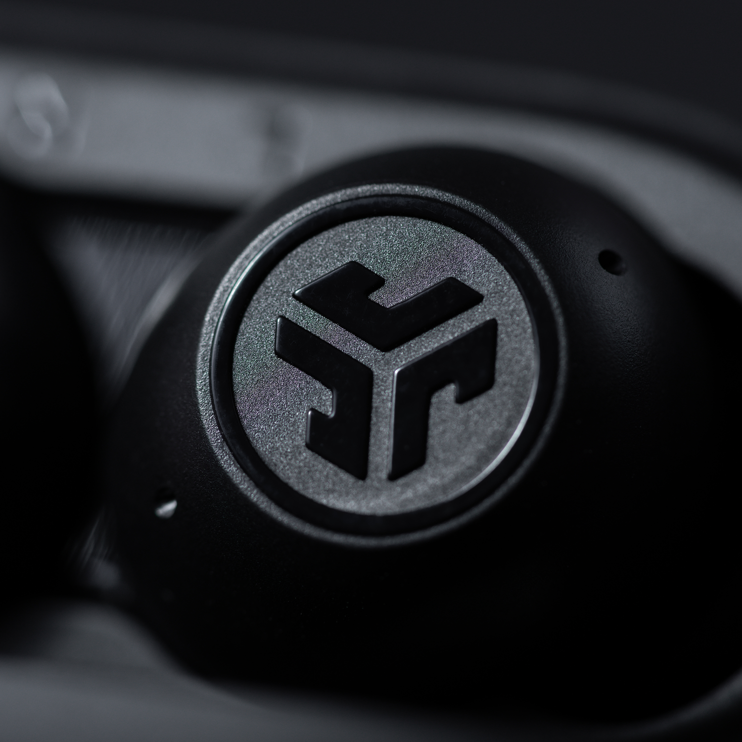 Close-up of a black earbud. The logo is visible.