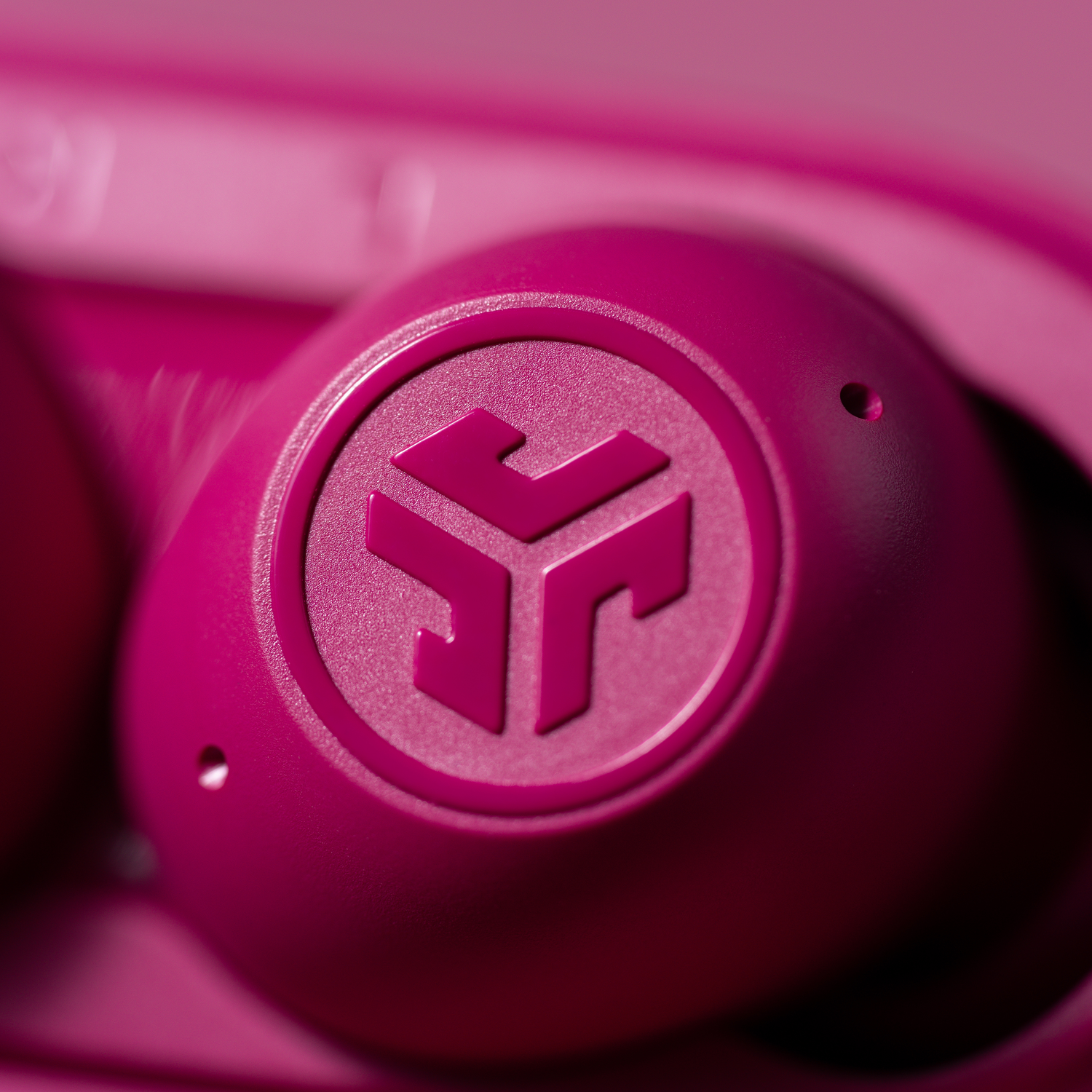 Close-up of a pink earbud with the JLab logo.