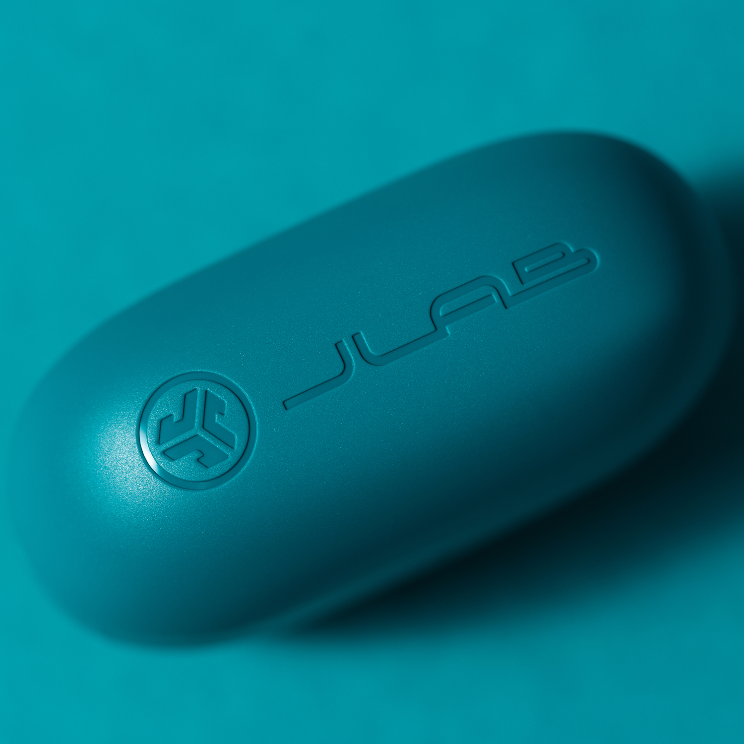 Tealblauwe JLab Go Air Pop oordopjescase op een teal achtergrond.